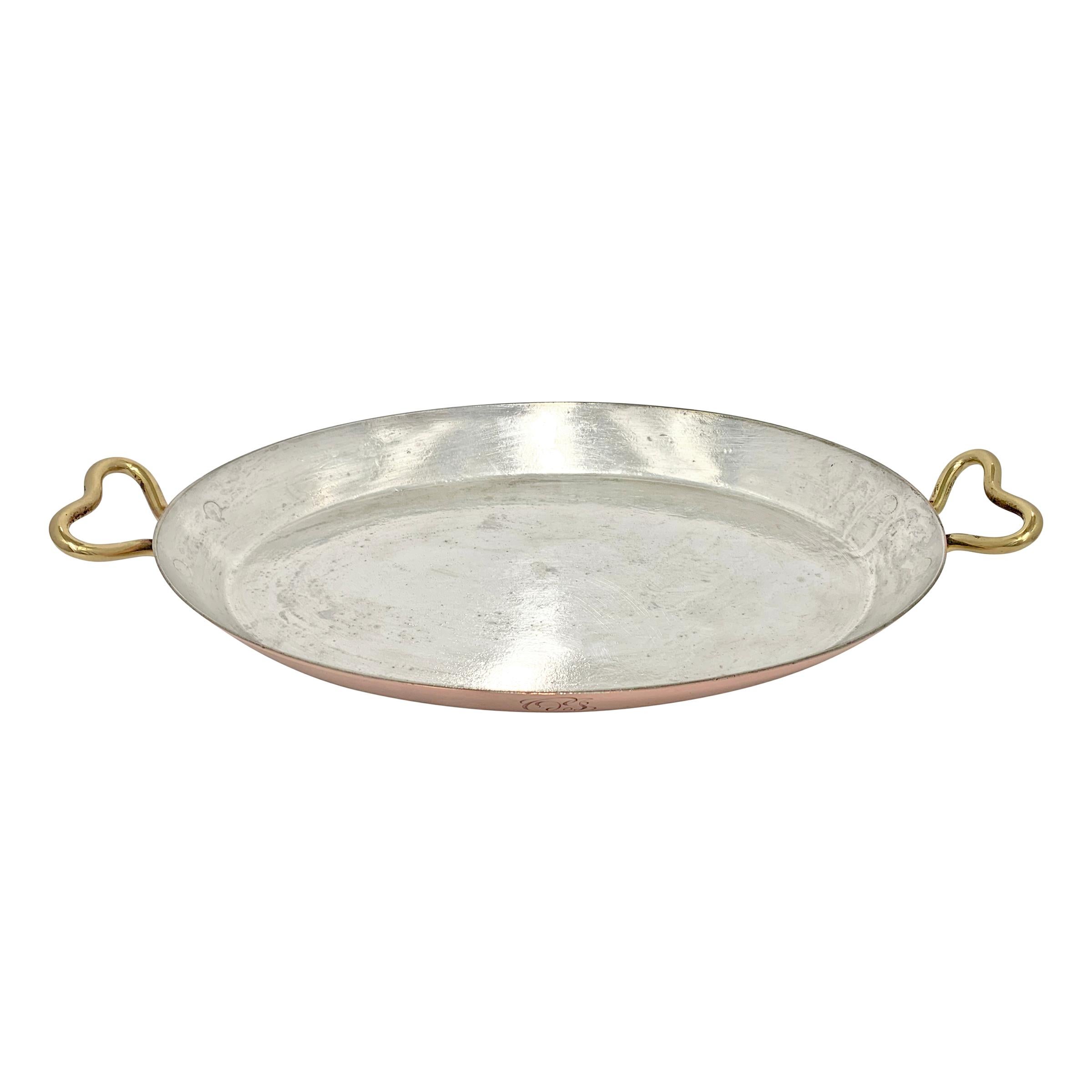 An early 20th century copper au gratin pan with bronze handles and an engraved monogram (