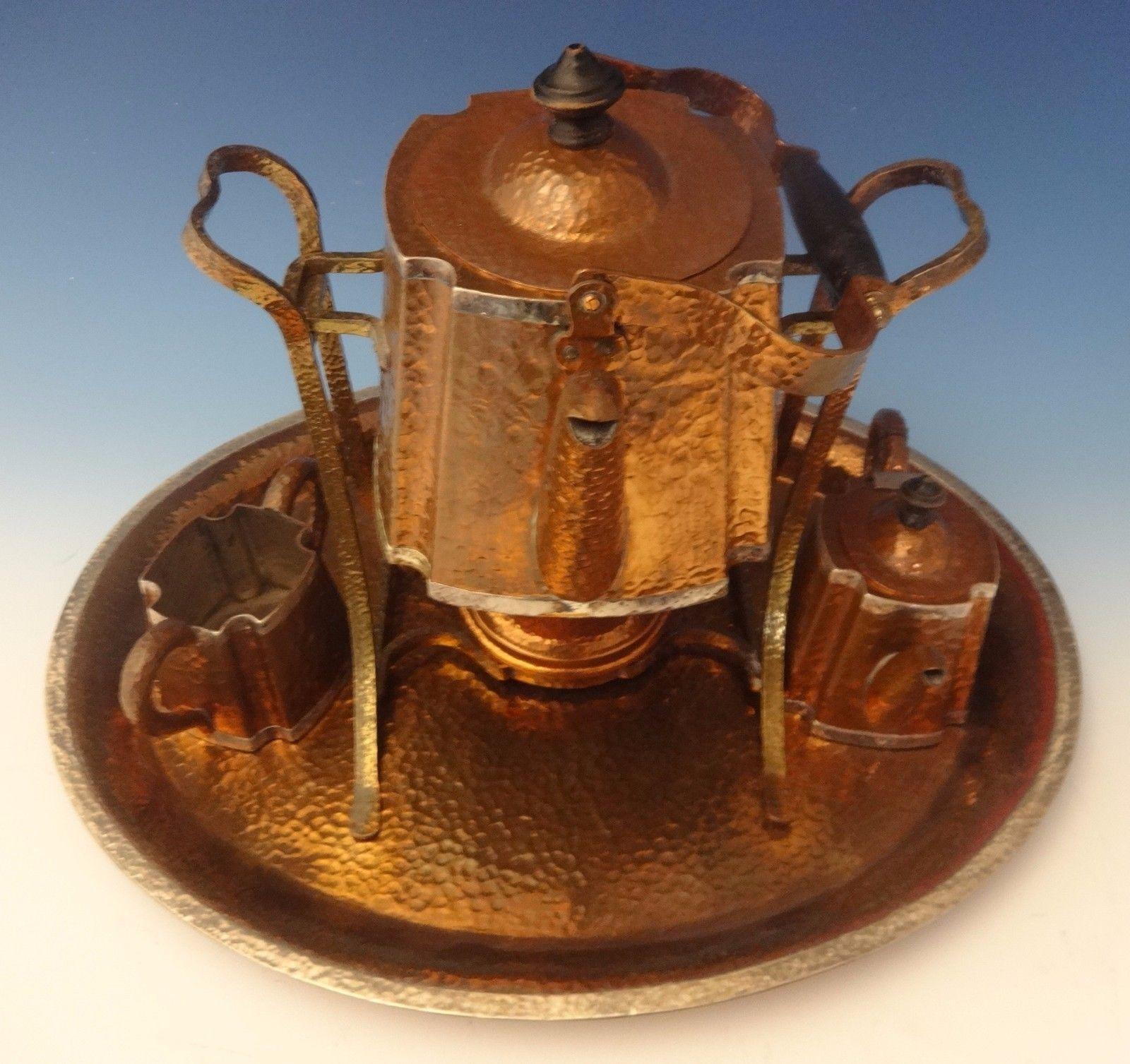 Joseph Heinrichs This very impressive Arts & Crafts 4-piece tea set was handmade by Joseph Heinrichs. It's made with hand-hammered copper with applied silver and brass. The set dates from circa 1905. The set includes: Tray: Measures 1 tall and 20 x