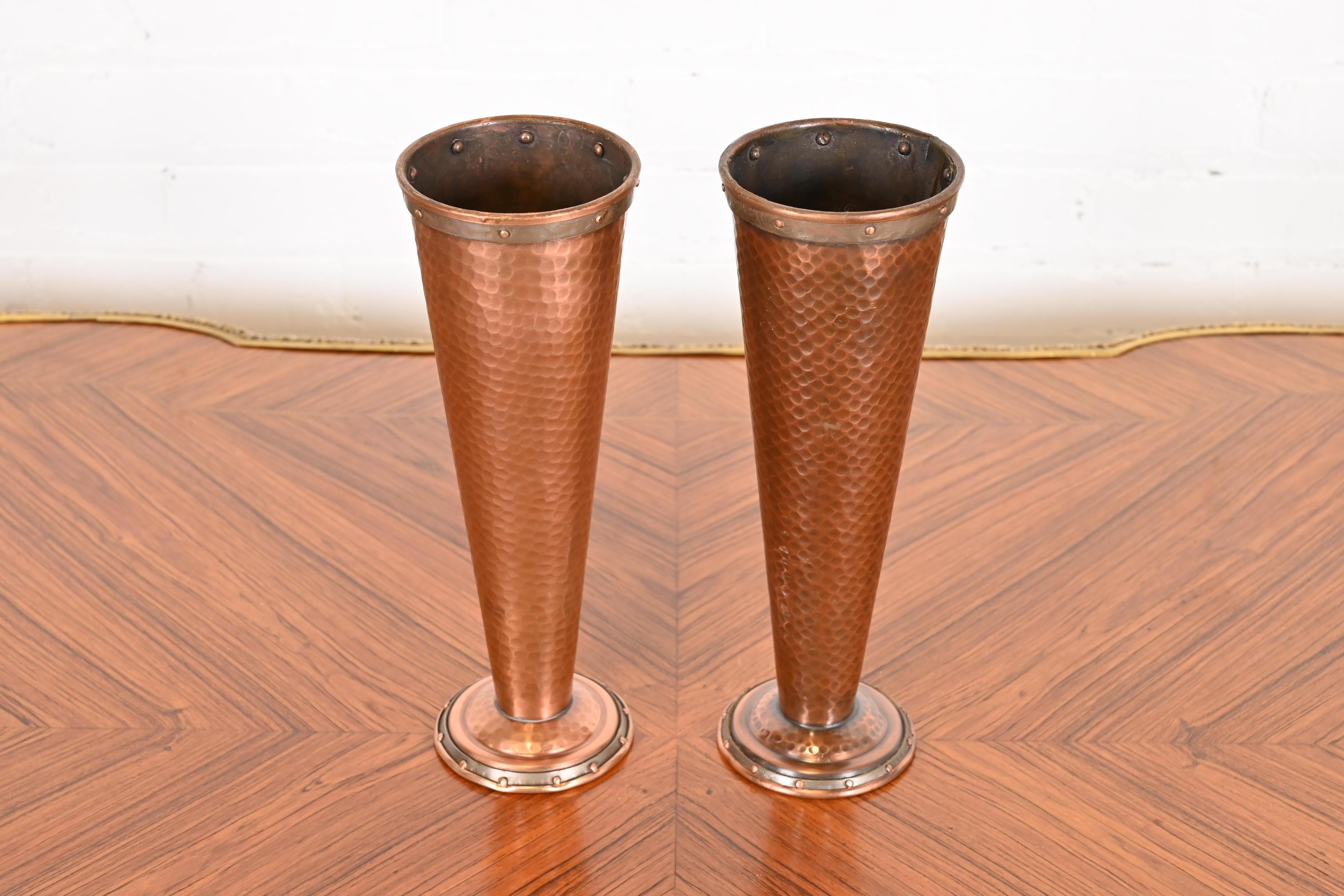 A gorgeous pair of Arts & Crafts vases

In the manner of Joseph Heinrichs

USA, early 20th century

Hand hammered copper, with riveted bands to tops and bases.

Measures: 4