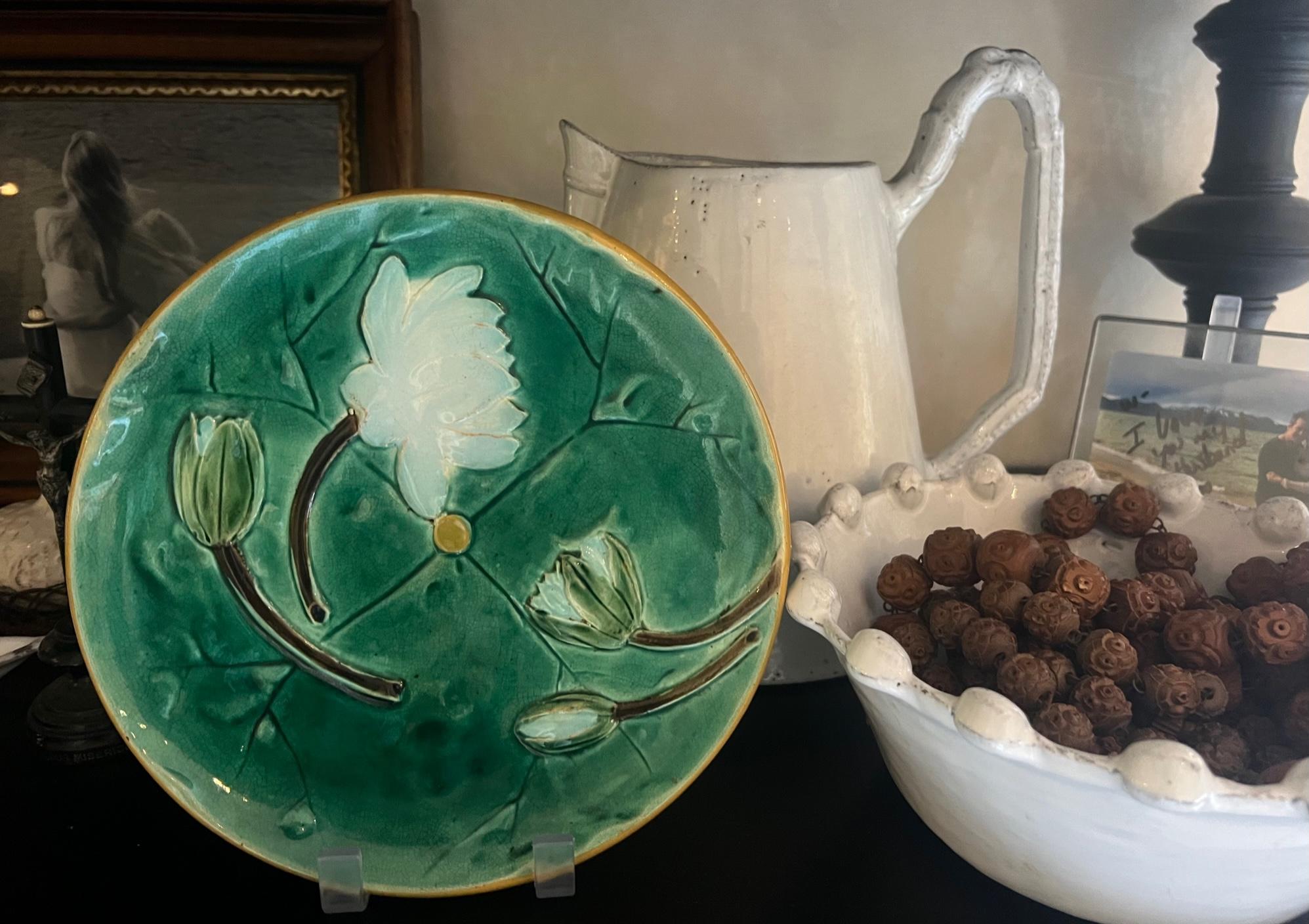Assiette à nénuphars ancienne en majolique, réalisée par Joseph Holdcraft vers 1885 en Angleterre.  Une assiette d'un vert éclatant avec des fleurs de nénuphar et un bord jaune.  La face inférieure porte le poinçon JH dans un cercle, indiquant