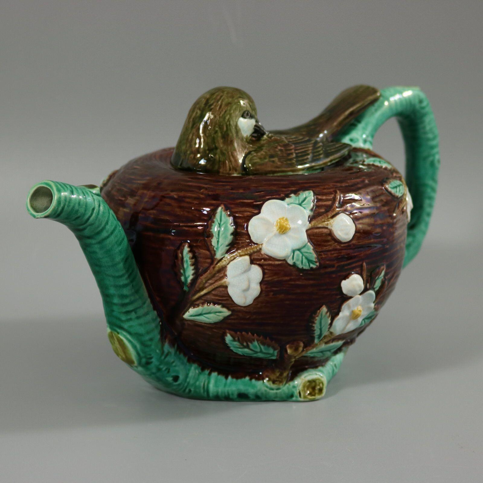 Holdcroft Majolica teapot which features the lid in the form of a bird roosting on its nest. The pot, modelled in the form of the bird nest is embellished with leaves and blossom, which sprout from the naturalistic branch effect handle. Colouration: