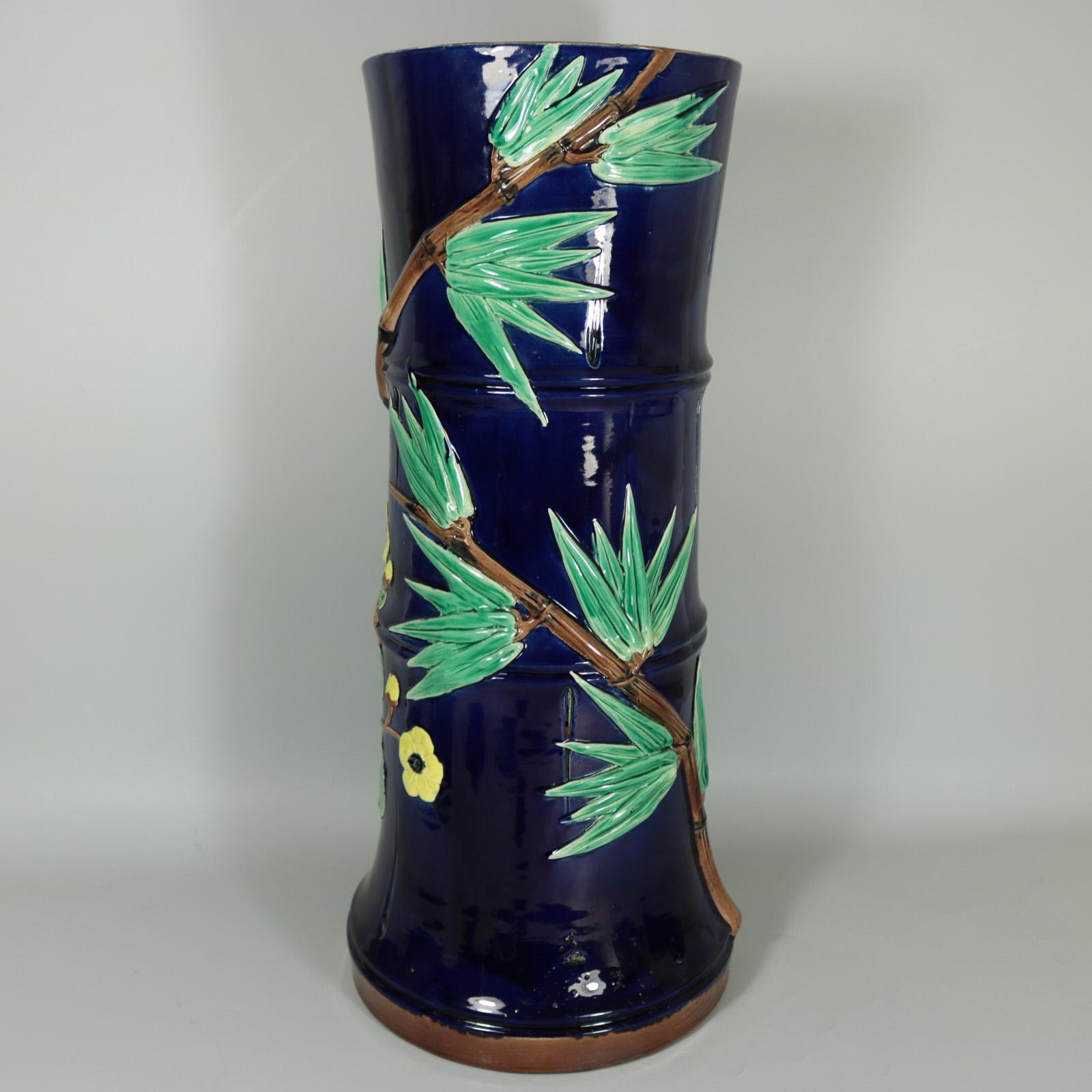 Holdcroft Majolica stick or umbrella stand which features leafy bamboo branches and peony flowers up the sides. Cobalt blue ground version. Coloration: cobalt blue, green, brown, are predominant. Bears a pattern number, '71..t'.