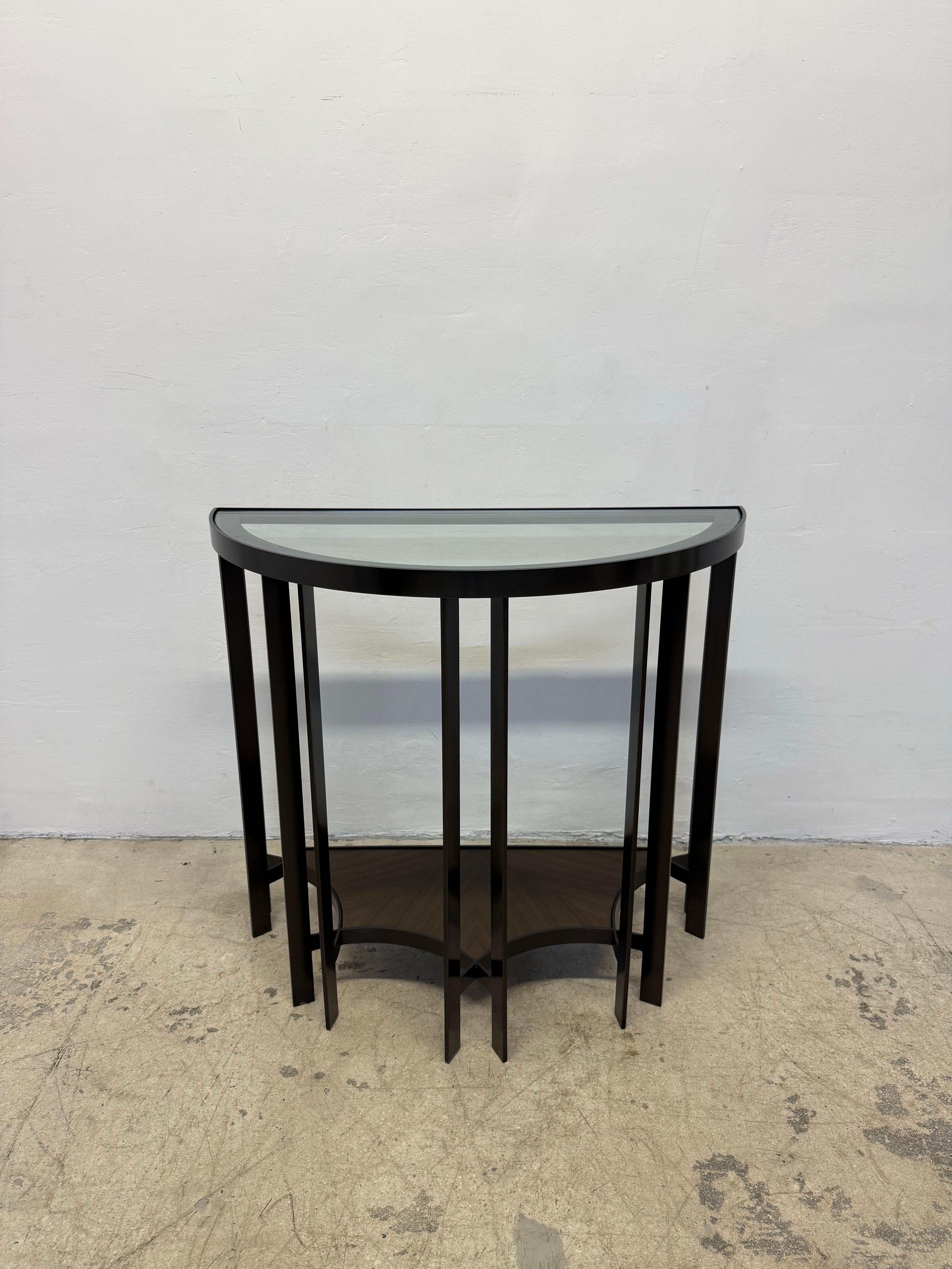Solid bronze base Demilune console table designed by Joe Jeup for the Legacy Collection by Donghia. The hand rubbed dark finish bronze frame holds a top glass shelf as well as a wood lower shelf. Maintains original seal with signature of designer.
