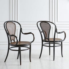 Joseph Kohn:: Paire de chaises en bois noir et cannage:: années 1900