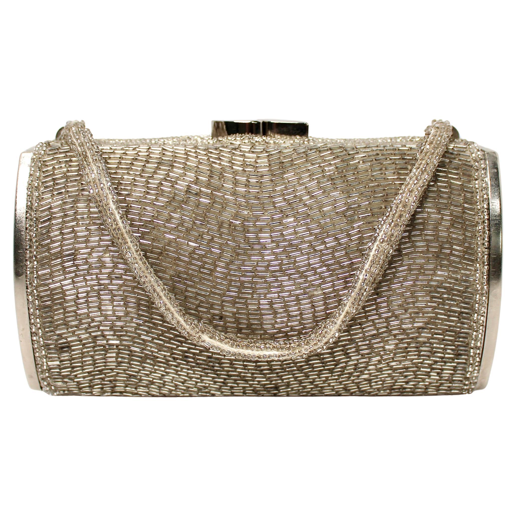 Esta impresionante obra de Joseph Magnin Co. Mini bolso de noche cilíndrico de cuentas plateadas de hacia los años sesenta que personifica el glamour y la elegancia de la moda de mediados de siglo. Elaborado con una meticulosa atención al detalle,