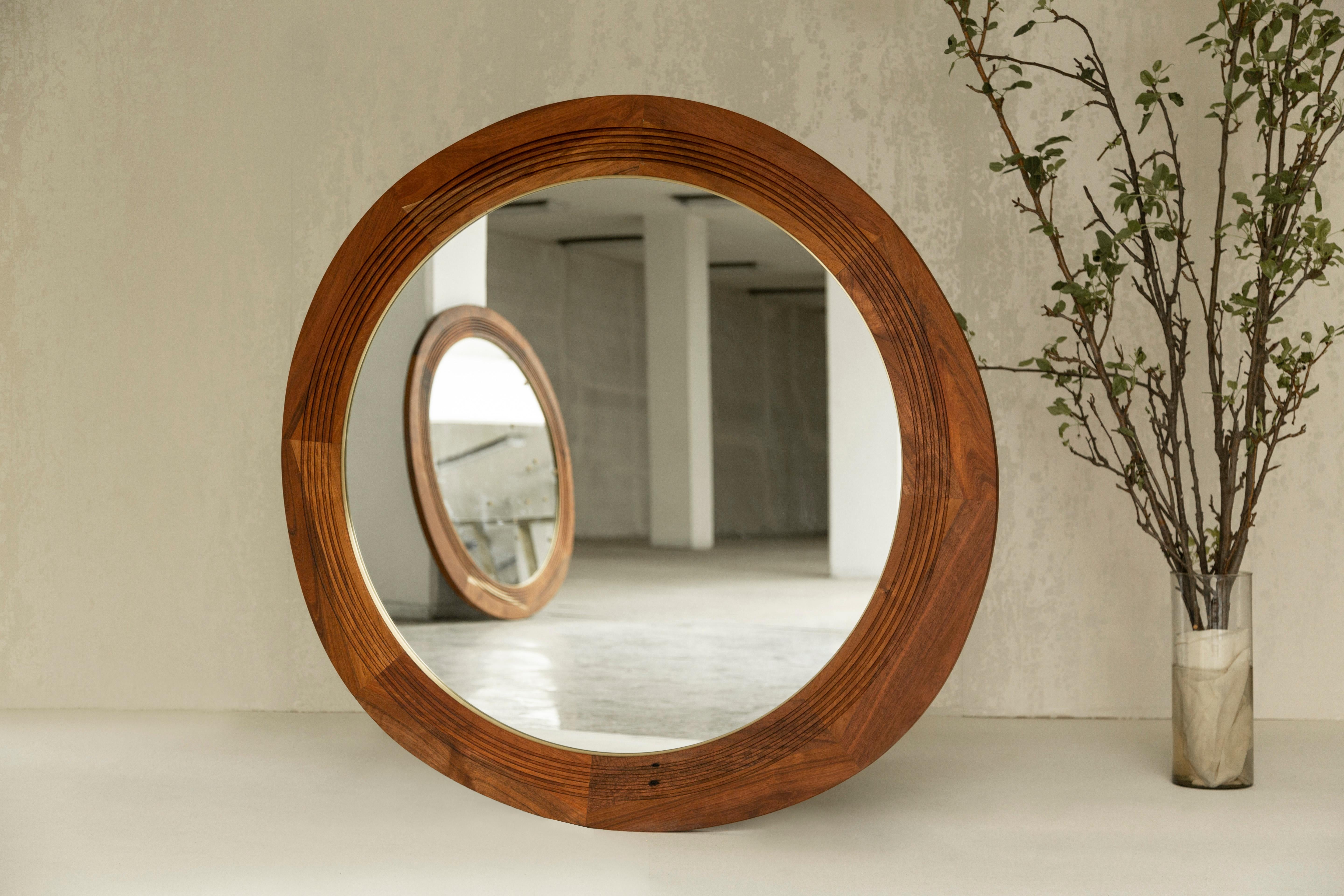 Der Joseph-Spiegel ist mit Messingdetails und schönen, in das Holz geschnitzten Mustern versehen. Die unregelmäßige Form bildet einen interessanten Kontrast zum inneren Kreis. Dieser Spiegel wurde nach Joseph Campbell benannt und bezieht sich auf