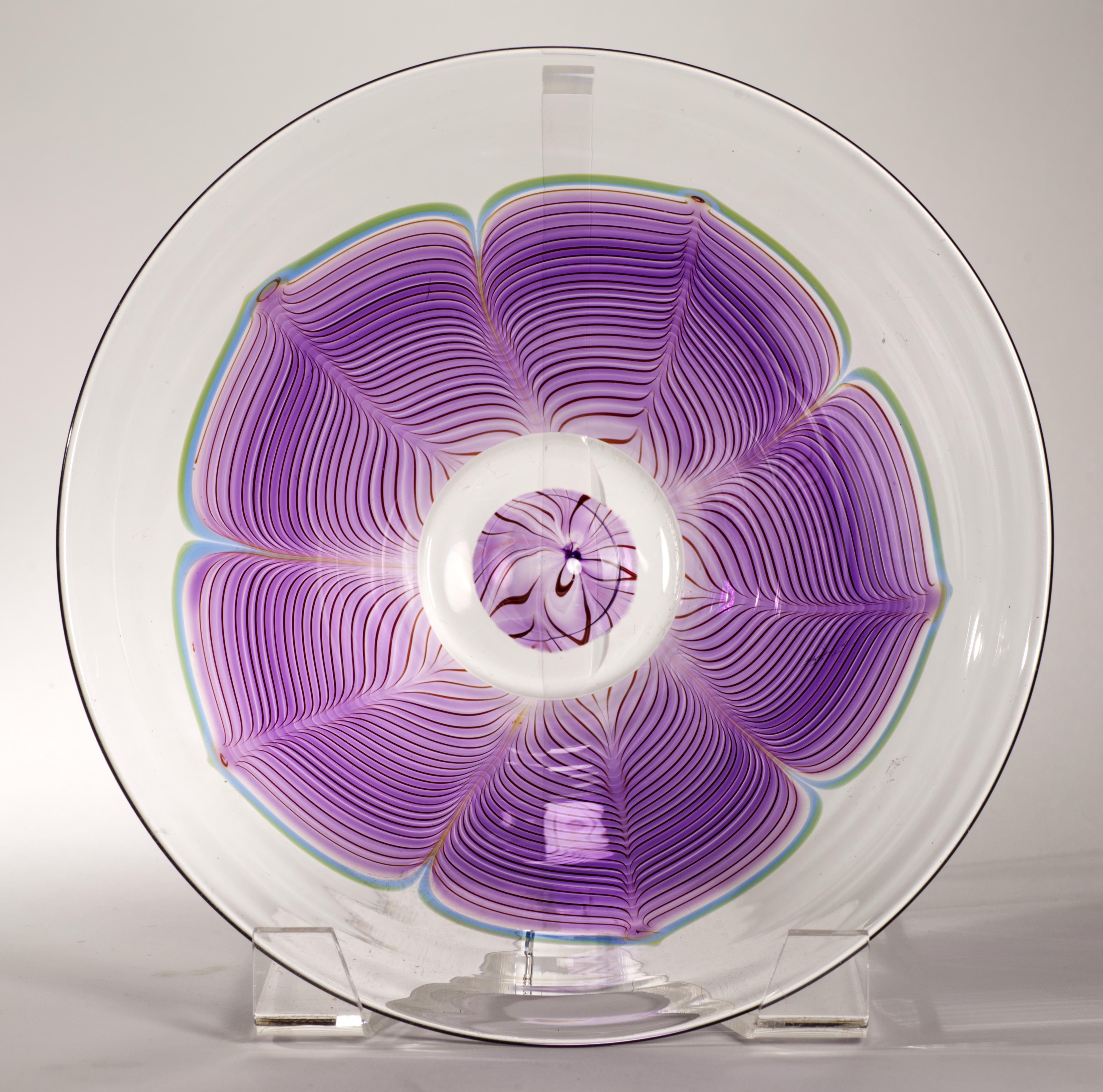  Ce bol en verre d'art vintage présente un décor frappant de style Art of Vintage avec des plumes tirées à 5 lobes en verre bleu, violet et rouge Bordeau, entouré de verre transparent. Le centre du bol présente un élément convexe, ajoutant un