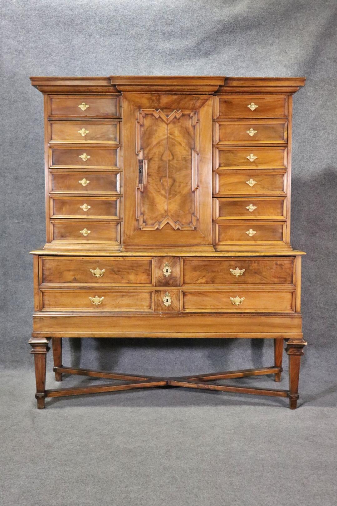 2 pezzi. Legno. Hardware in metallo. Il pezzo superiore ha 12 cassetti a coda di rondine. Un'anta contenente 2 cassetti a coda di rondine. Il fondo presenta una scrivania a ribalta con 4 cassetti a coda di rondine. 70 7/8