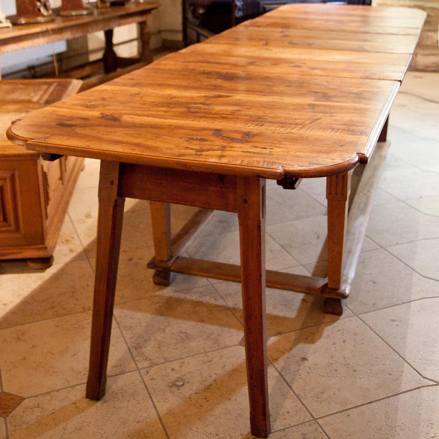 Very long dining table in its original condition, the legs are slightly tapered and are connected through strutting. Foldable legs support the extendable tabletop. Very nice natural patina.