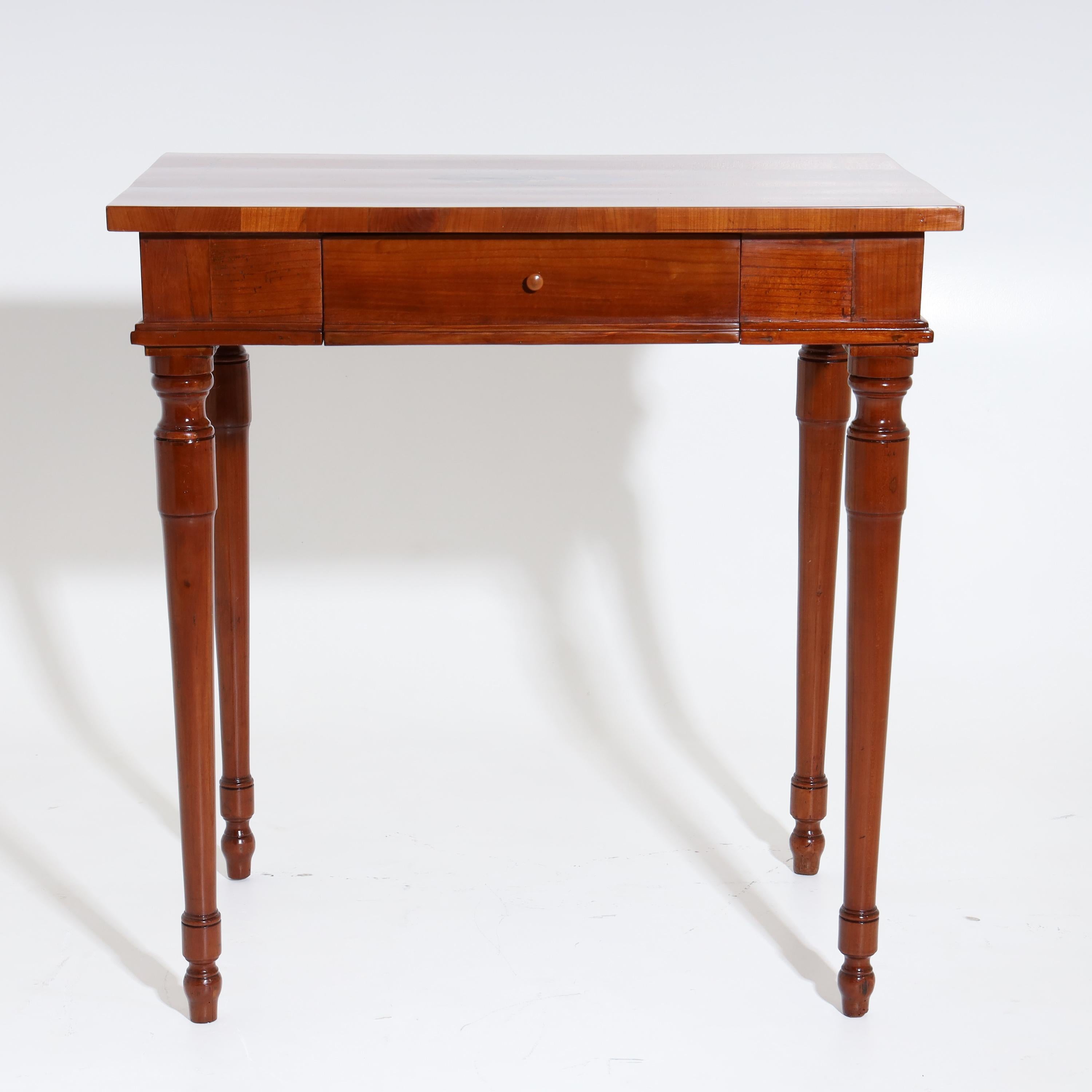Side table made of cherry, standing on conical and balustered pointed legs, with straight frame and one drawer. The slightly protruding tabletop is decorated with a medallion-shaped inlay with putto and bird.