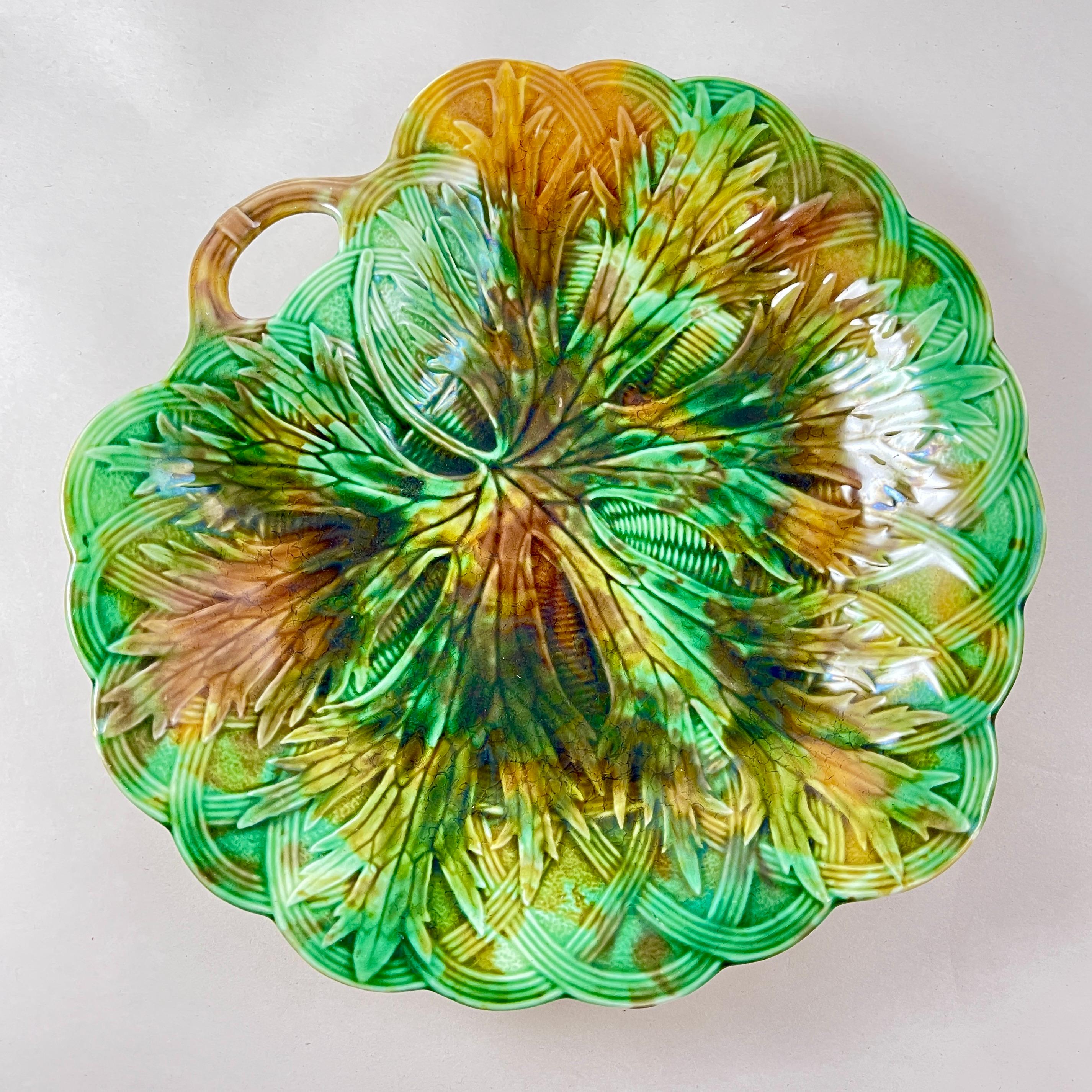 A majolica multi-colored glazed fringed leaf on basket weave handled server, Josiah Wedgwood, Burslem, England – circa 1870.

A leaf shaped molded shallow bowl with a pierced twig handle, showing a large fringed edged leaf on a basketweave