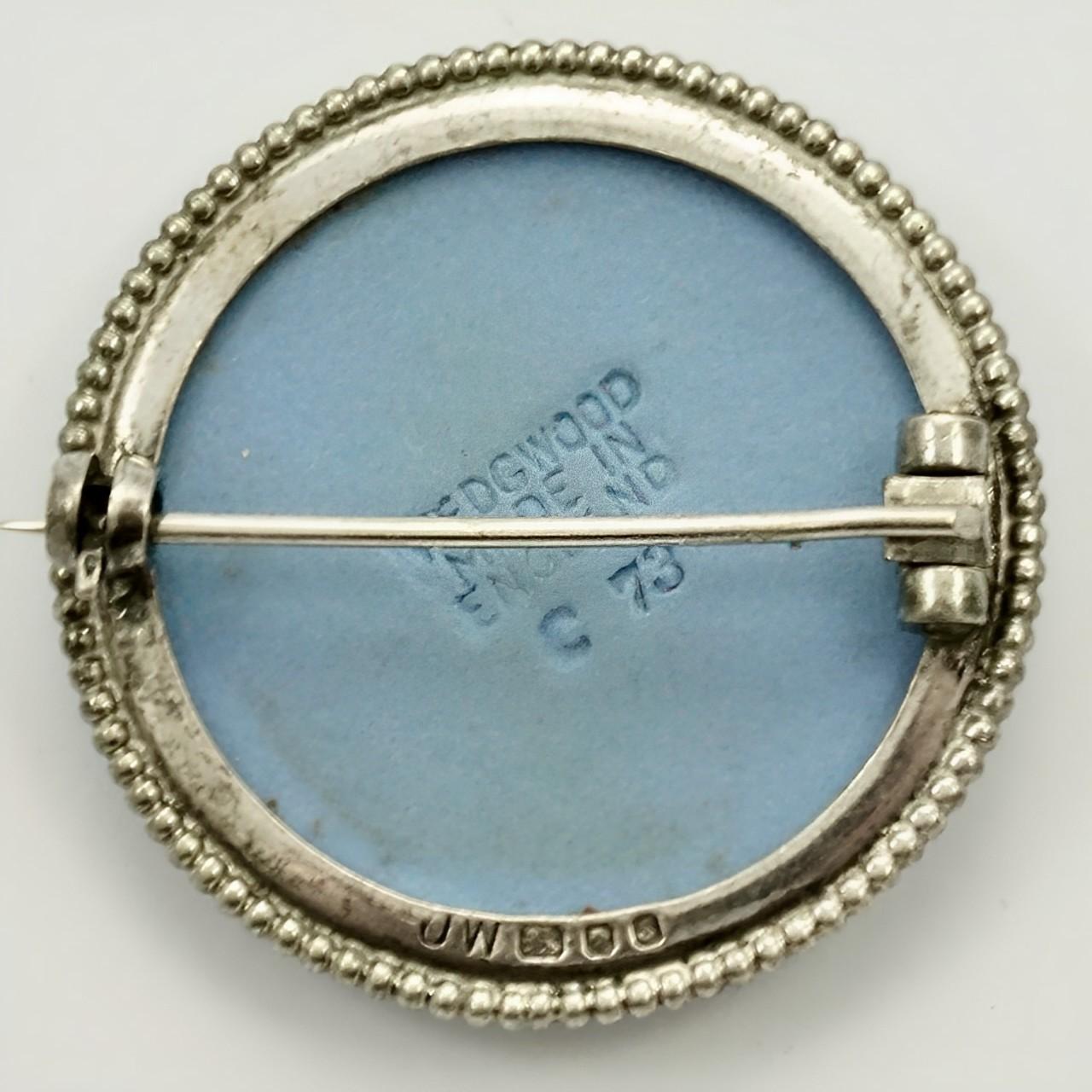 Wedgwood sterling silver and blue jasperware brooch, featuring a classical relief figure with bow and arrows. Measuring diameter 3.1 cm / 1.2 inches. The silver is stamped with a lion, a leopard's head, and the letter S. The makers mark is JW. This