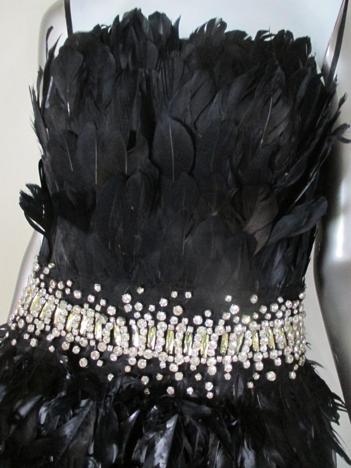 This is a Vintage black evening gown with inside lining short dress. 
This exquisite gown is embroided with black iridescent feathers and silver color stones.
The dress has a zip and hook-and-eye side closure. 
Its worn and has some wear.
There are