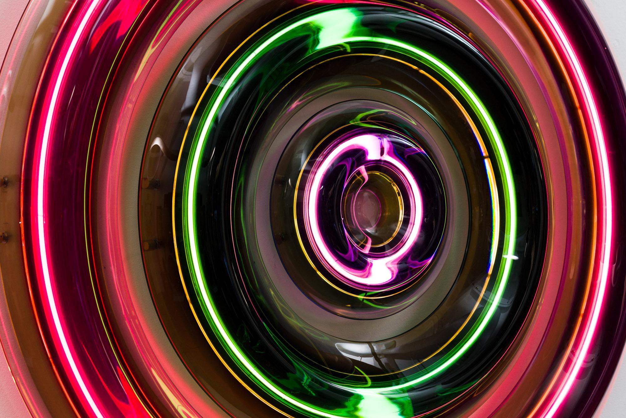 Inspired by the 1970s and the Space Age, this organic illuminated wall sculpture from Draga and Aurel, called Joy Circle, features a series of concentric dimmable neon rings embedded in combined layers of jewel toned epoxy resin. Complementary hues