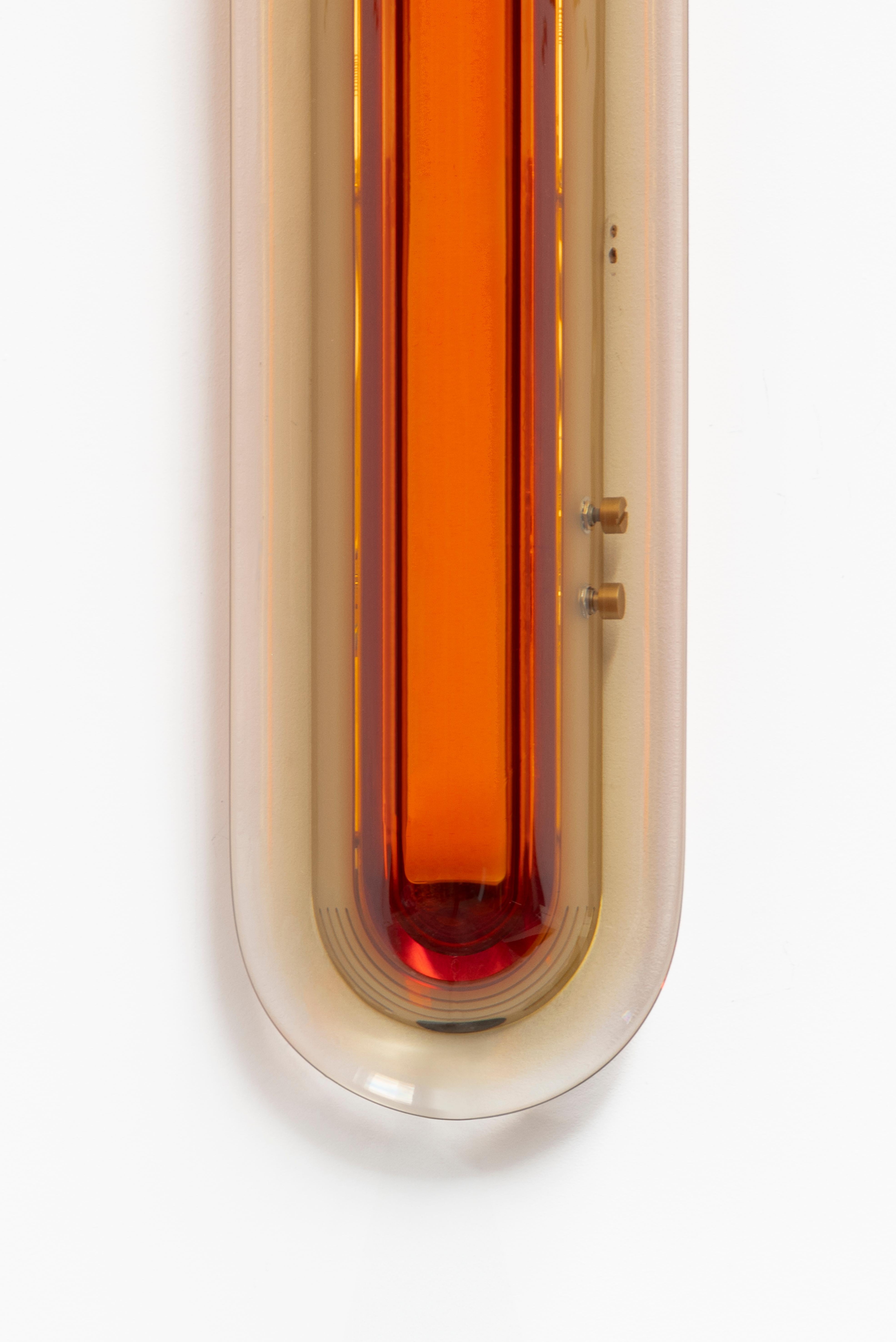 S'inspirant de l'ère spatiale, l'applique Joy apparaît comme une sculpture lumineuse qui attire le regard. Ses couleurs vibrantes sont méticuleusement fabriquées à la main dans notre atelier en superposant de la résine époxy pour obtenir des teintes
