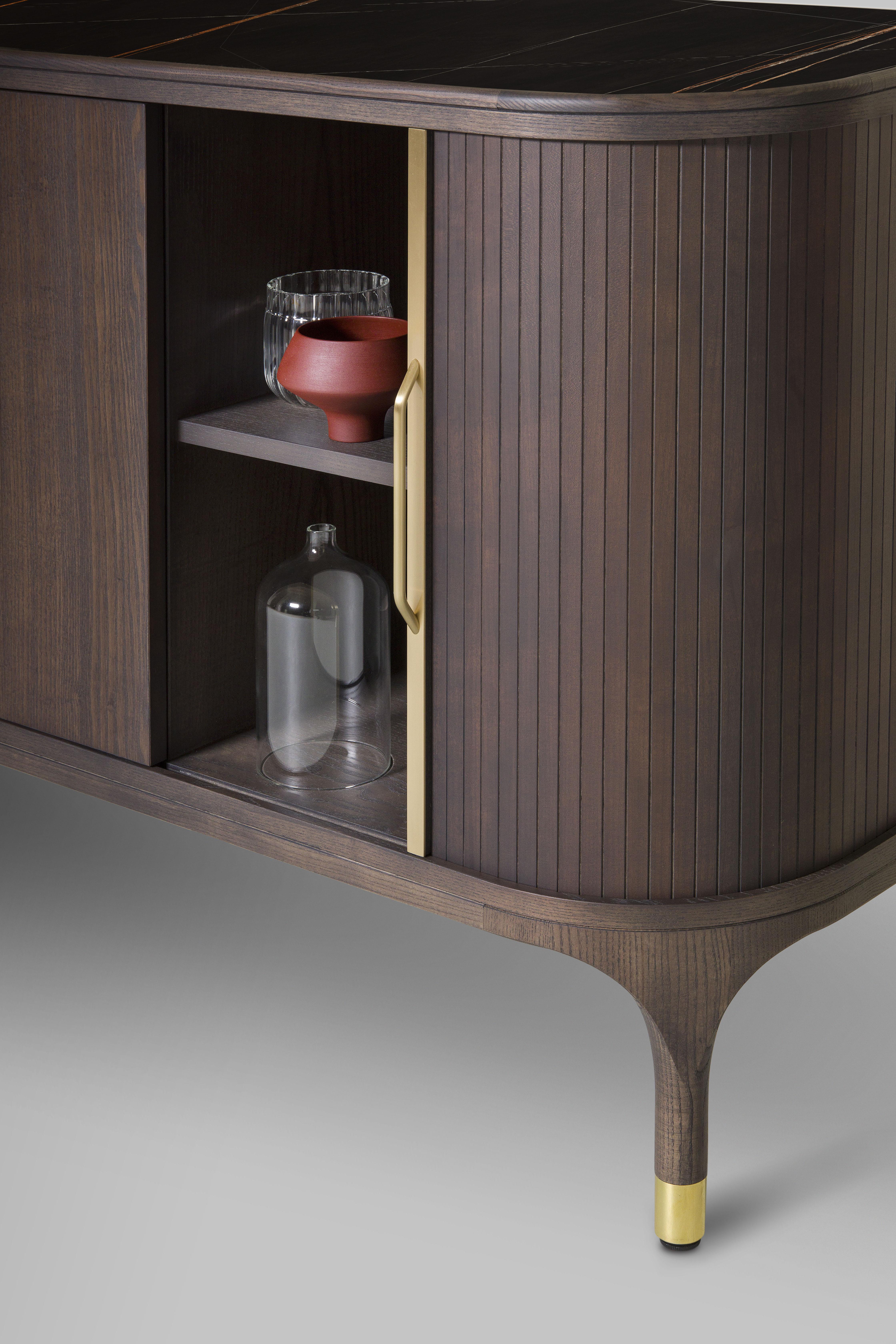 Joyce Sideboard im zeitgenössischen Stil aus Eschenholz mit Messingdetails.
Zwei zentrale Türen und zwei seitliche Schiebetüren mit handgefertigten Messinggriffen.
Platte aus Holz, Glas oder Marmor-Keramik 
Entworfen von Libero Rutilo.
Maße: L 212,