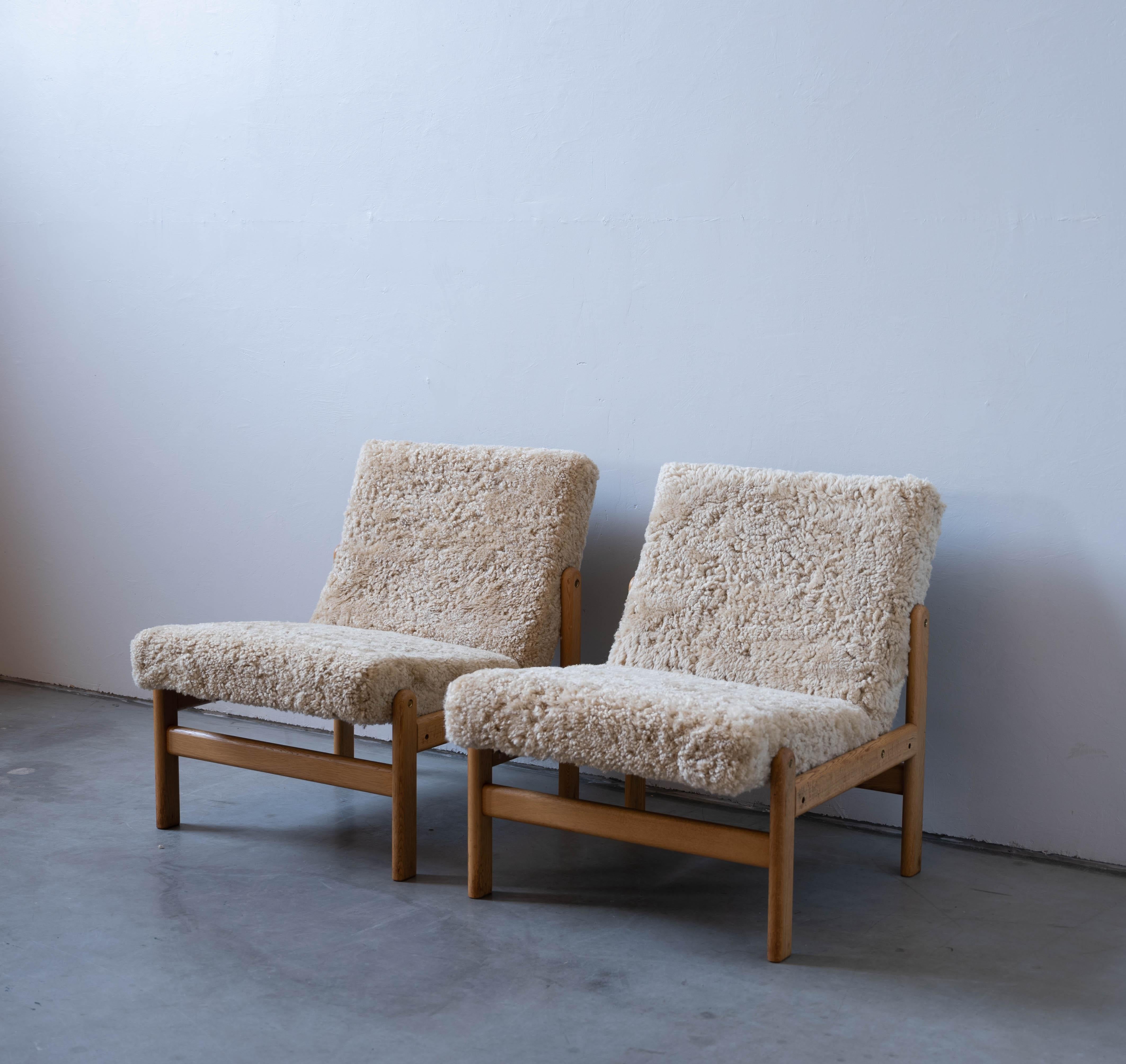 A pair of oak and shearling / sheepskin slipper chairs designed by Jørgen Bækmark for FDB Møbler, Denmark, 1950s. 

Present pair was produced for and used in Kerteminde Town Hall.

