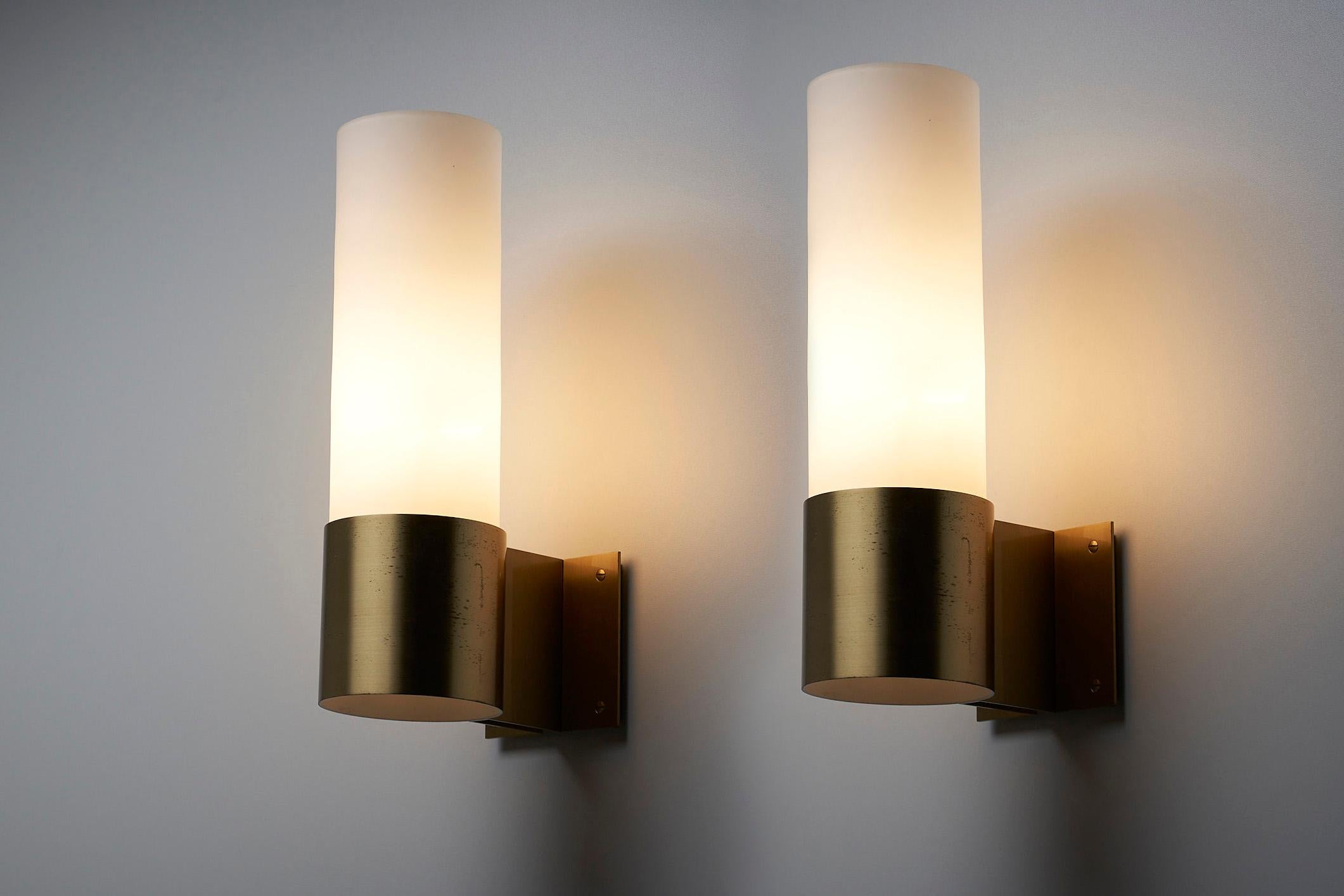 Add a touch of minimalist elegance to your space with the Brass With Glass Wall Sconce by Fog&Mørup, designed by Jorgen Bo in Denmark in 1960. This wall sconce showcases a sleek and refined design that seamlessly combines brass and glass
