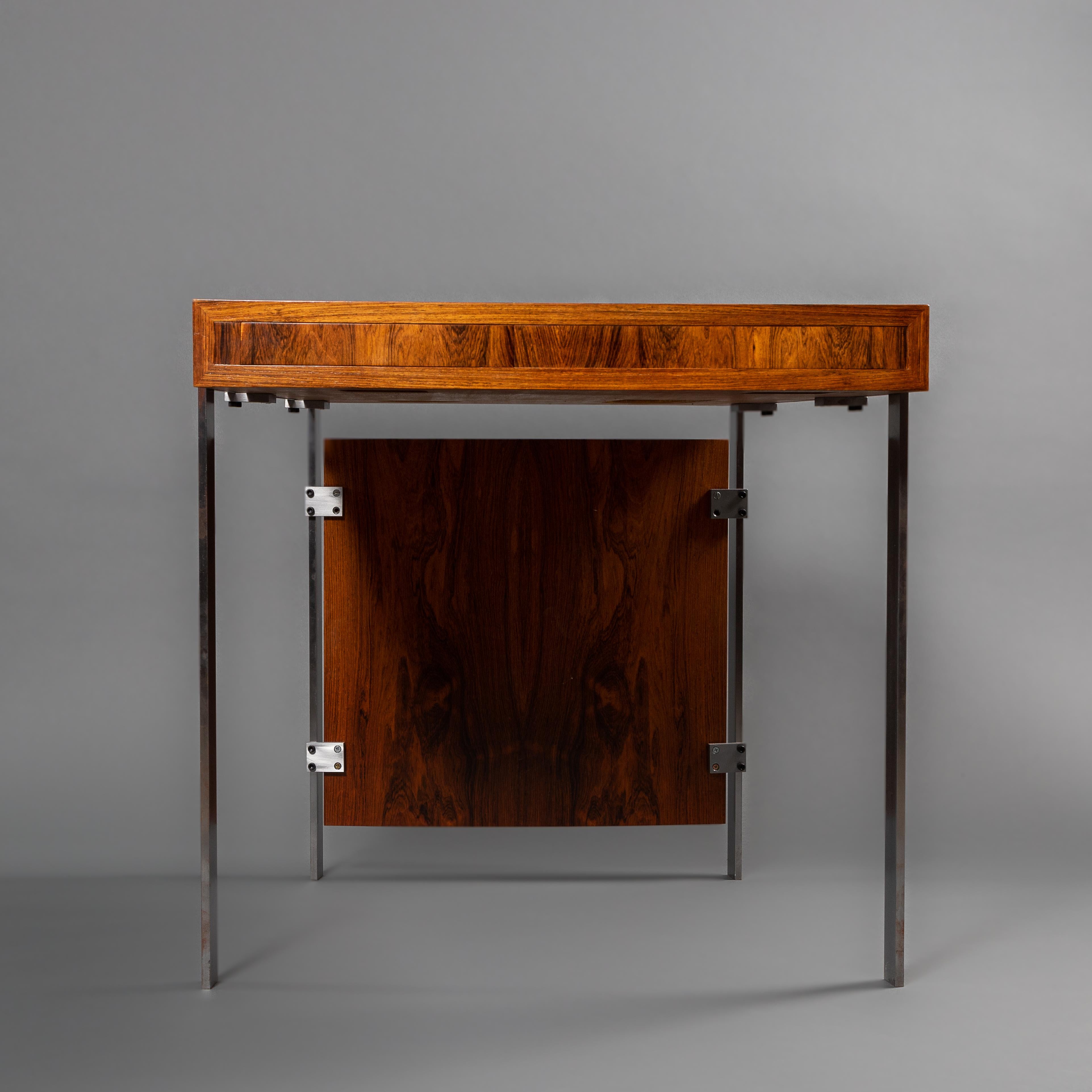 Free-standing rosewood desk, front with two drawers, one drawer with integrated ash tray, satin polished steel frame. Designed 1962. Manufactured by Borella-Hansen & Co and Herluf Poulsen, frame manufactured by Herluf Poulsen. 

The tables are