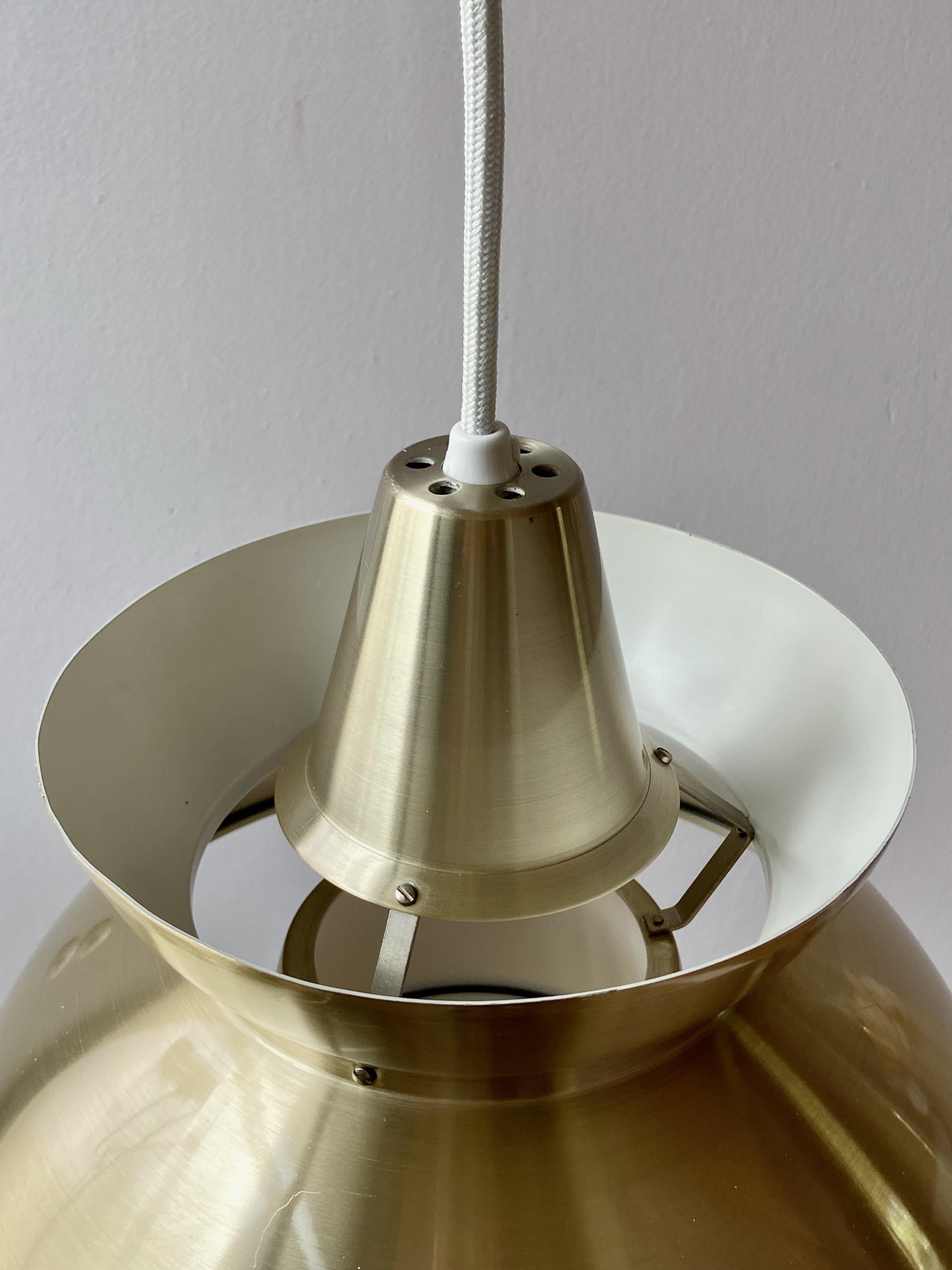 Nice vintage Søværnspendel looks like the Louis Poulsen Doo-Wop pendant lamp but is produced by Nordisk Solar and Made in Denmark. Brass colored metal and white laqured metal inside. The lamp is in good condition. No parts missing, with new fabric
