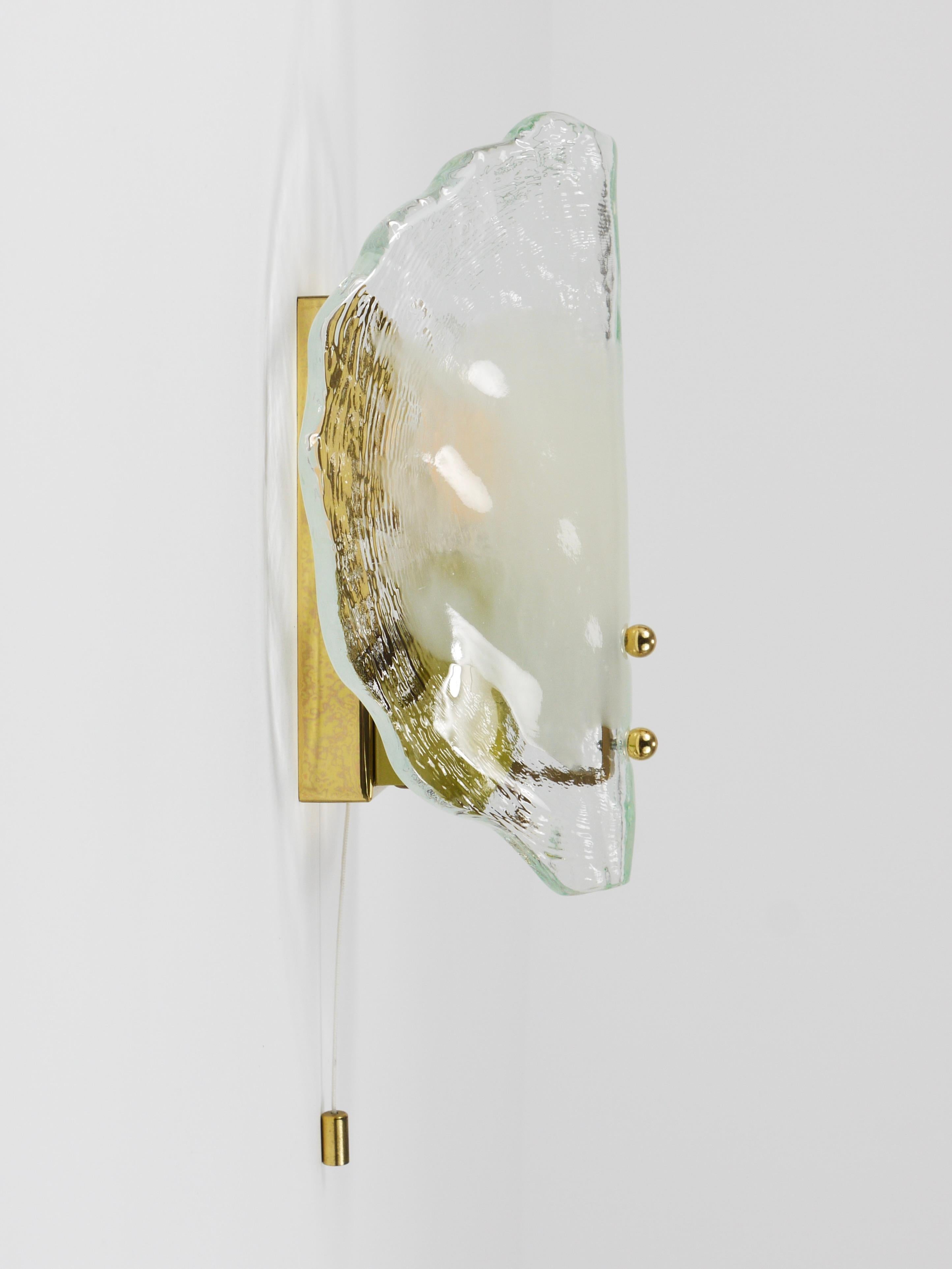 A beautiful, high-quality Mid-Century Modern wall lamp from the 1970s, manufactured by J.T. Kalmar, Vienna, Austria. The base is made of brass with a folded and curved petal shaped shade, made from solid, thick, double-layered clear and opal white