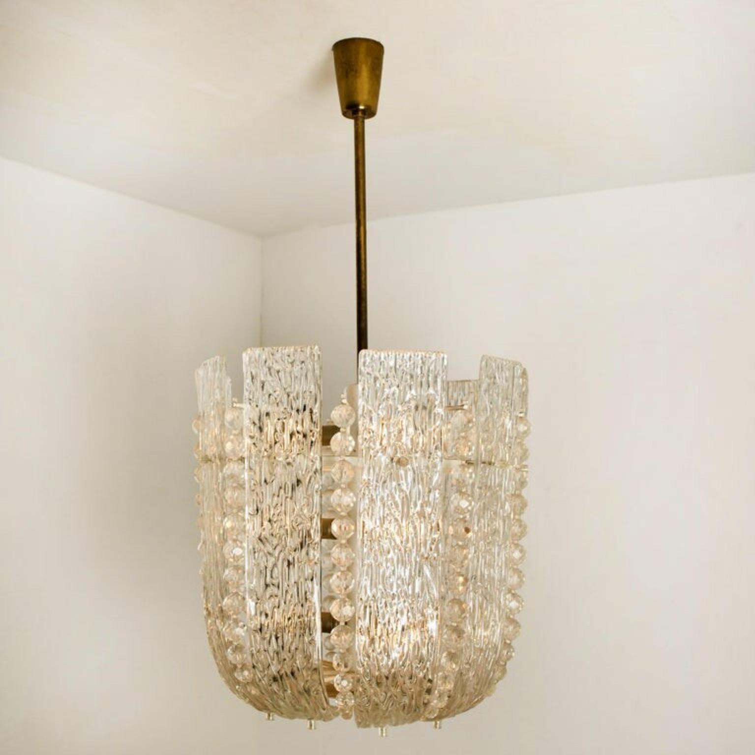 Stunning chandelier by Kalmar composed of large textured glass slabs and crystal pearls on an enameled brass hardware.

The glass has a beautiful wave pattern, what gives a nice diffuse light effect and a nice pattern on ceiling, walls and