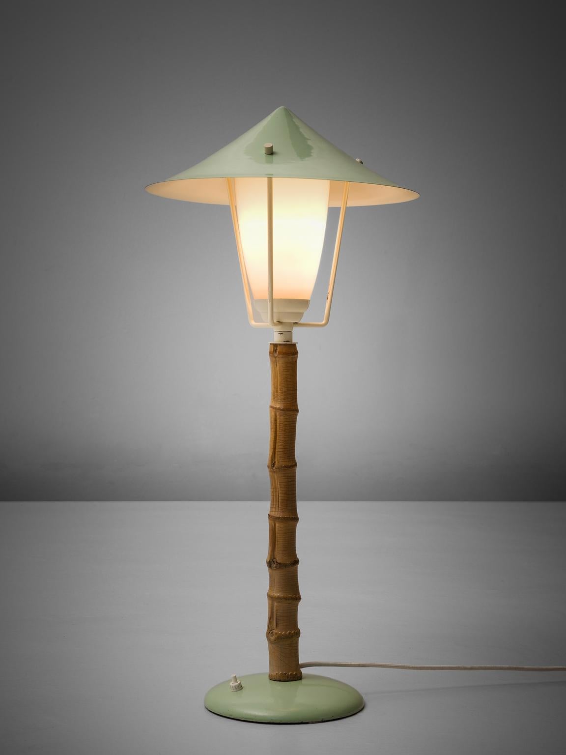 J.T. Kalmar, table lamp, metal, faux-bamboo and glass, Austria, 1950s. 

Frivolous table lamp, or small floor lamp in green coated metal. This lamp reminds of a tradition garden light. The garden is literally represented in this light by the