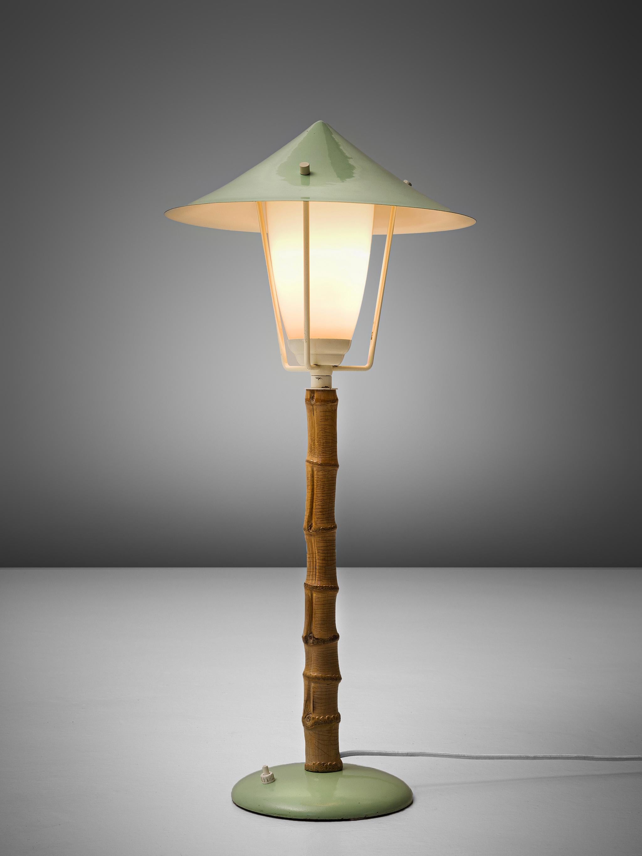 J.T. Kalmar, table lamp, metal, faux-bamboo and glass, Austria, 1950s. 

Frivolous table lamp, or small floor lamp in green coated metal. This lamp reminds of a tradition garden light. The garden is literally represented in this light by the