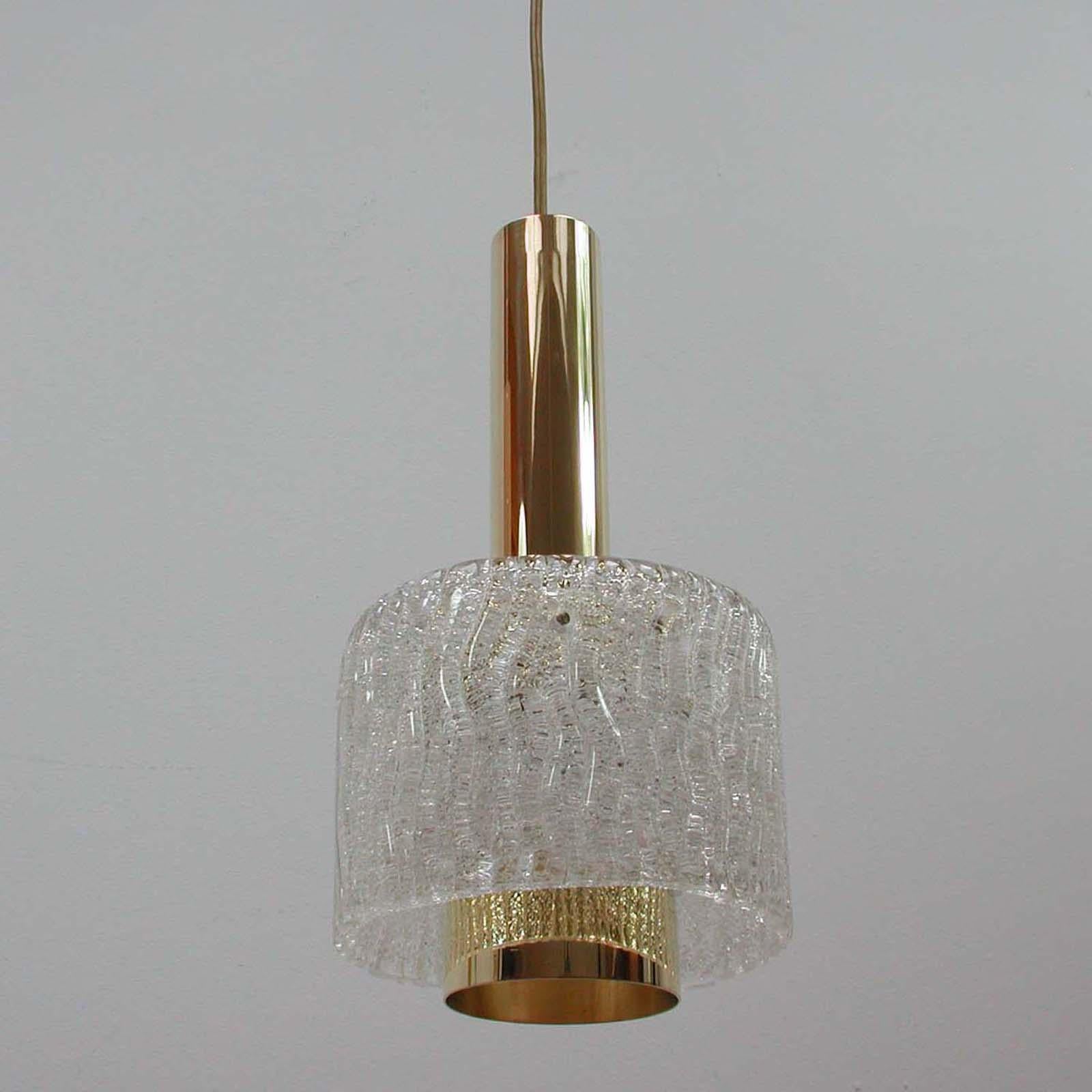 Diese schöne Pendelleuchte aus der Jahrhundertmitte wurde in den 1950er Jahren von JT Kalmar in Österreich entworfen und hergestellt. Sie hat einen Korpus aus Messing und einen Lampenschirm aus strukturiertem Glas. Die Messingteile sind
