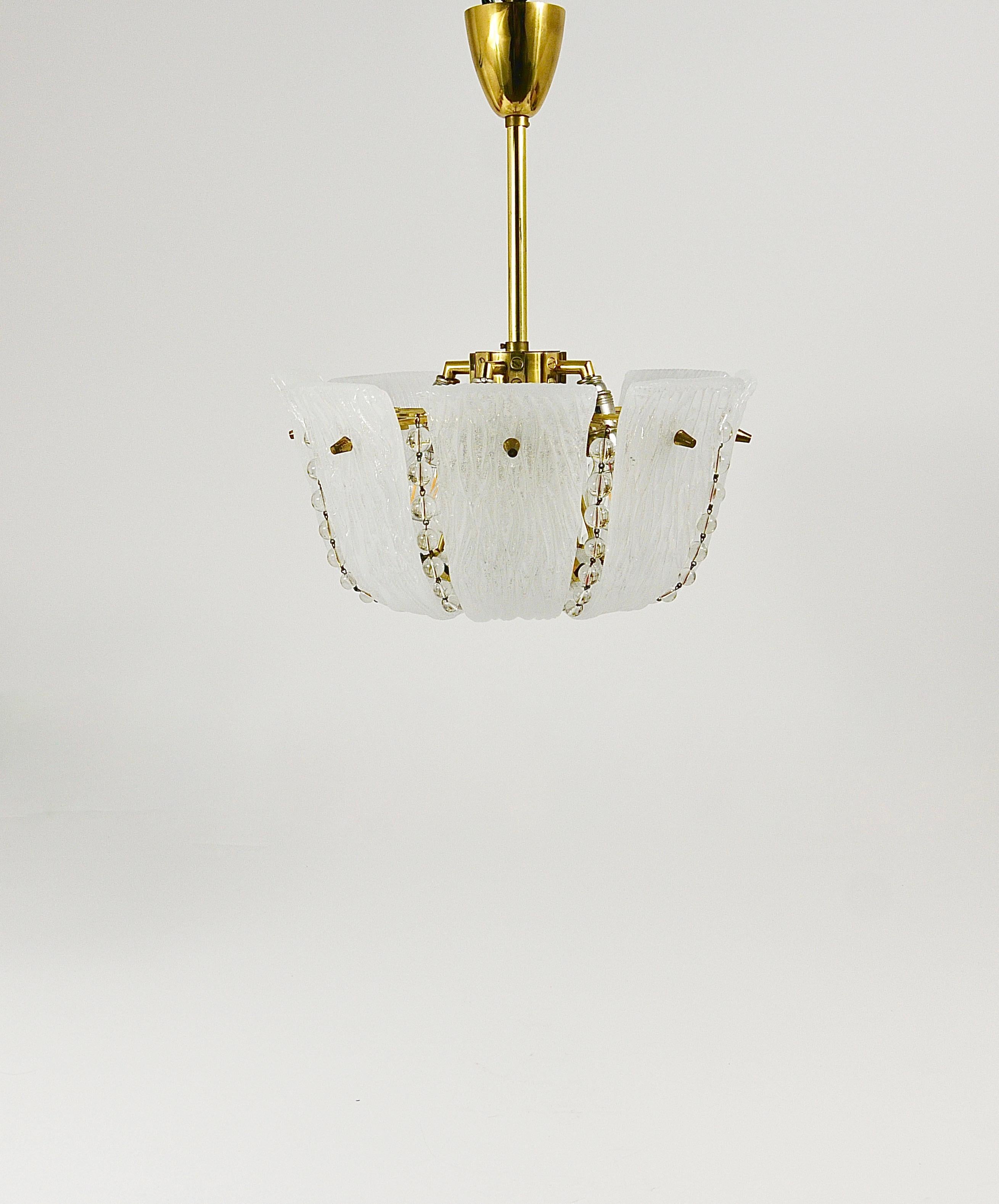 Ein schöner, zierlicher österreichischer Messinglüster aus der Mitte des Jahrhunderts aus den 1950er Jahren, hergestellt von J.T. Kalmar, Wien. Dieser elegante Vintage-Kronleuchter besteht aus acht zart geschwungenen, strukturierten weißen