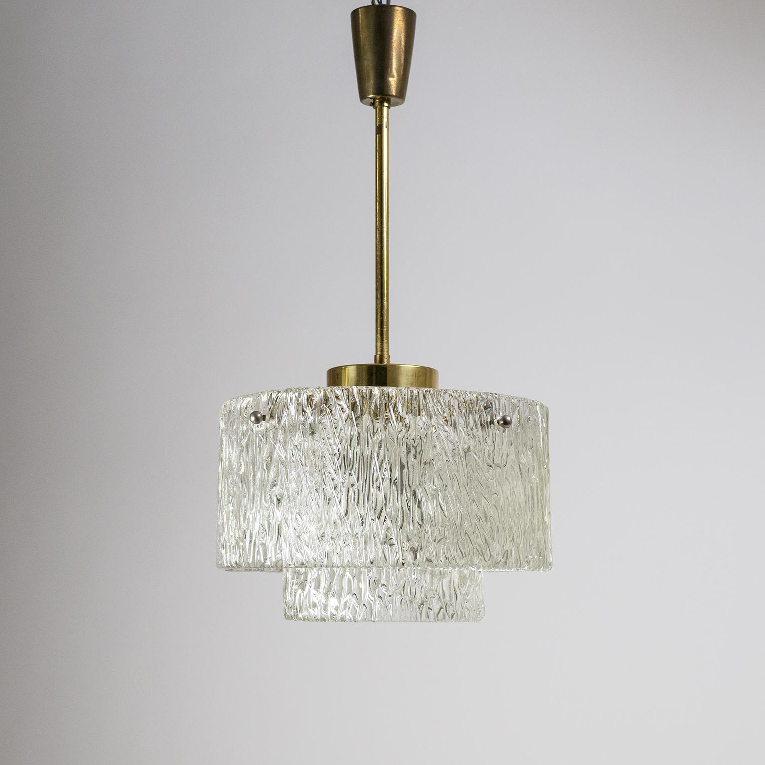 Very nice J.T. Kalmar textured glass and brass chandelier from the 1950s. Suspended from brass hardware and held in place by nickelled knobs are two tiers of heavily textured glass. Very good original condition with patina on the brass parts. One