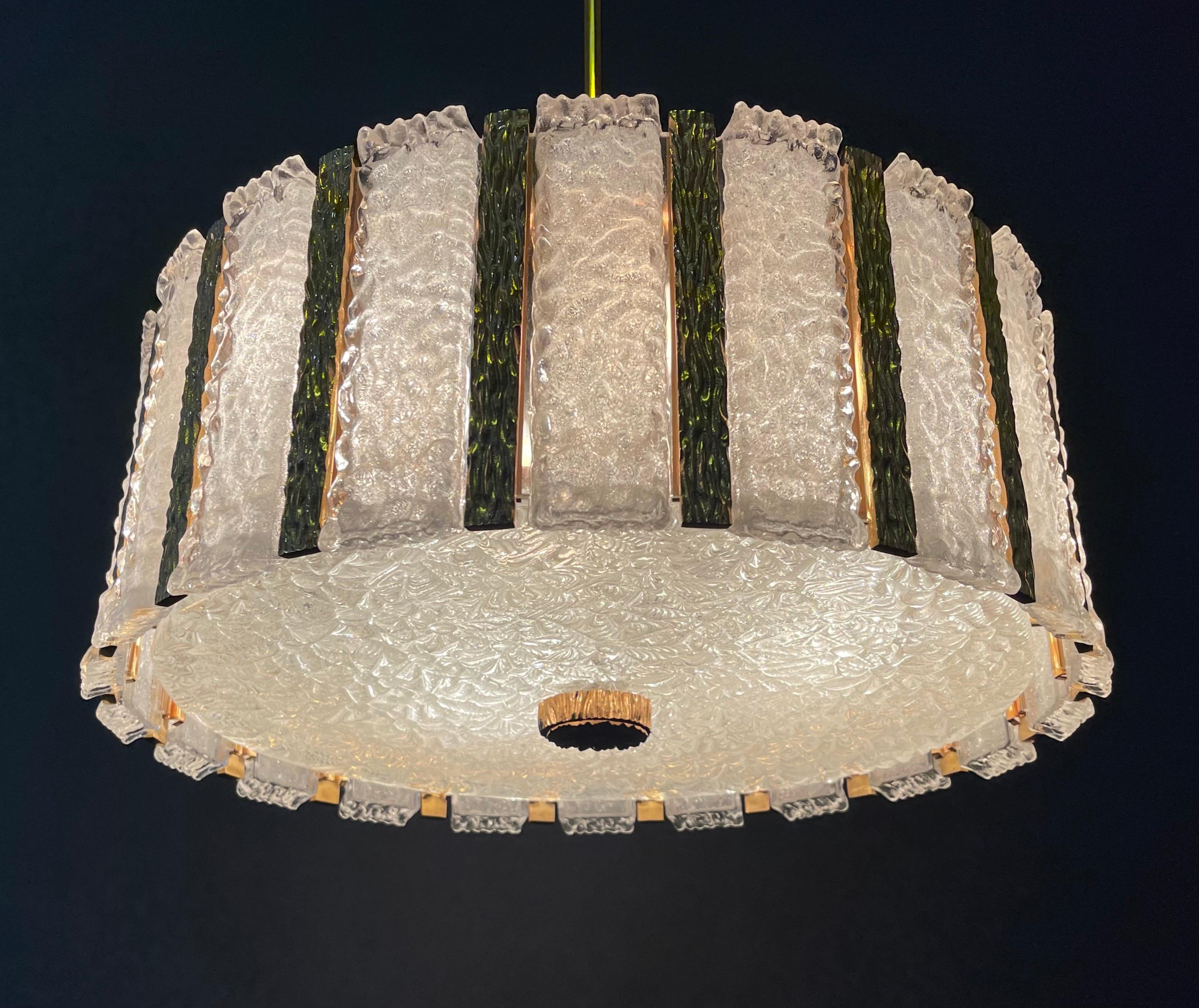 Splendida coppia di due lampadari a tamburo di J.T. Kalmar, Austria, anni '60 circa.
I lampadari sono realizzati in bronzo dorato e vetro di Murano color ghiaccio.
Zoccolo: 9 x e14 per lampadine a vite standard.
 