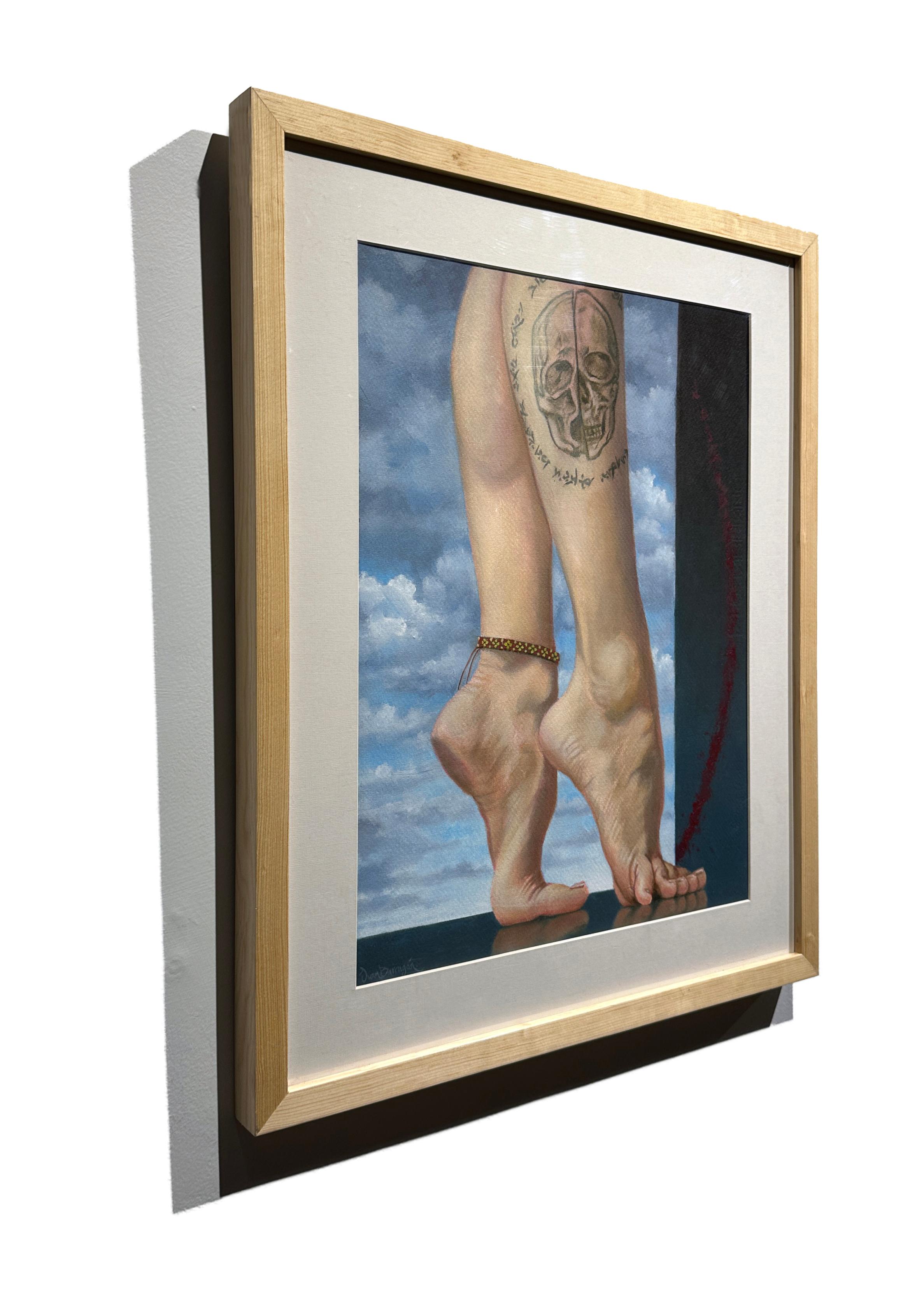 A pair of muscular legs emblazoned with a skull tattoo are set against a bright blue sky in Juan Barragán's painting titled 