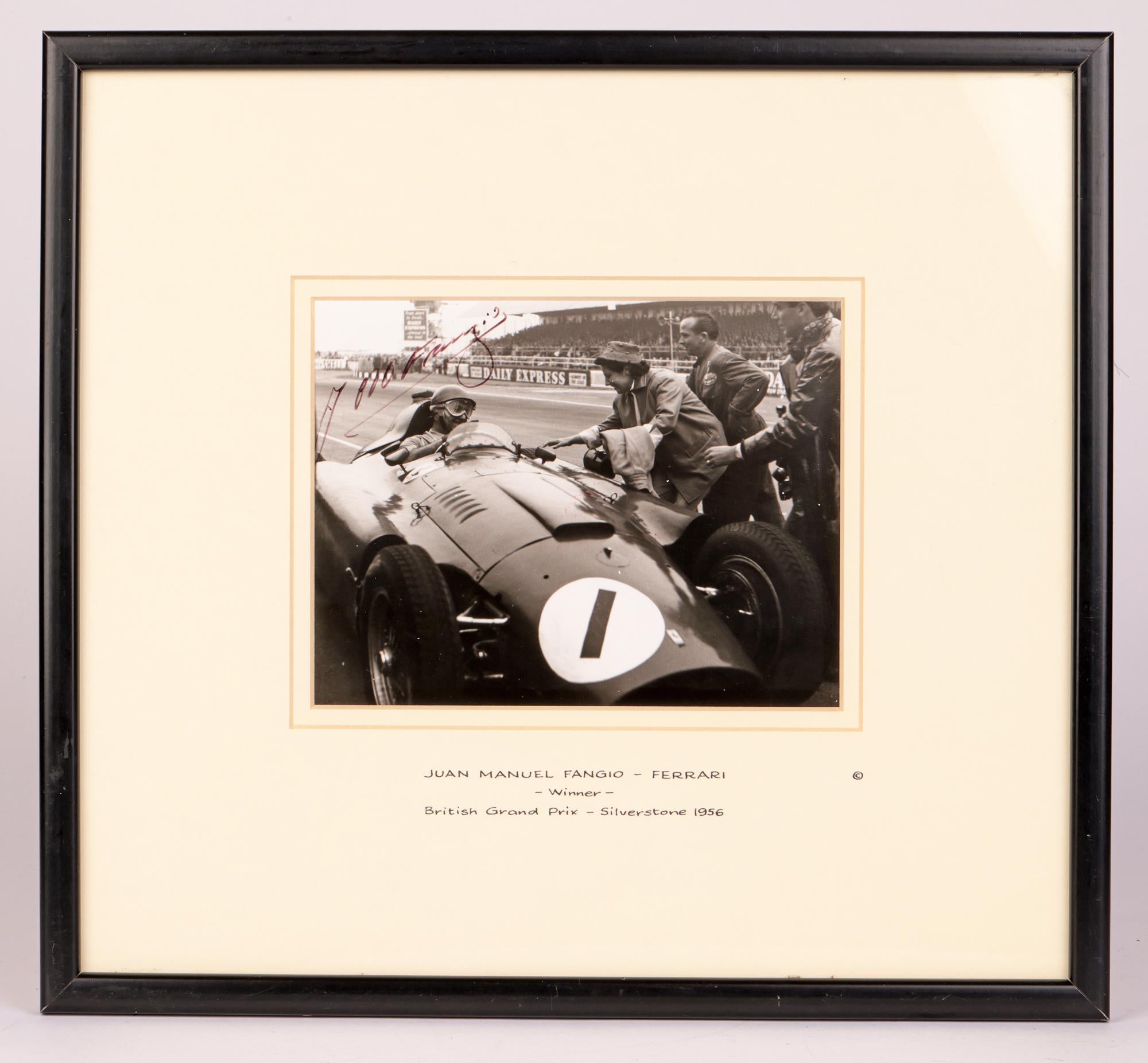 A superb piece of motoring history is this framed black and white silver gelatin print of Juan Manuel Fangio sat in his Ferrari and being congratulated following his victory in the British Grand Prix at Silverstone in 1956. The print is signed in
