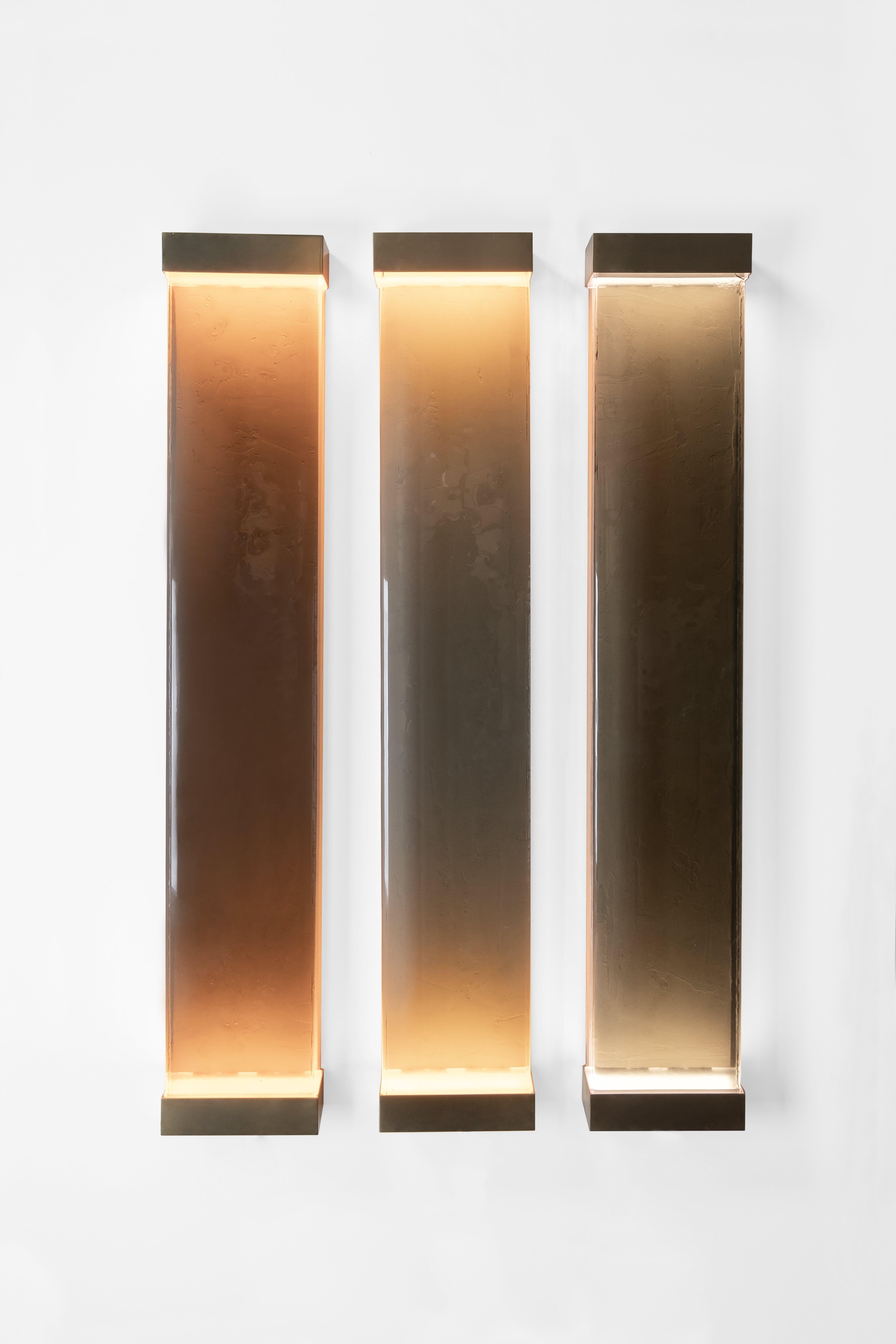 Drawing inspiration from minimalism, Jud lamps pay tribute to artist Donald Judd. The various shades of translucent glass and resin filters have been melded together to create a cohesive and balanced color scheme. Each piece consists of a brass