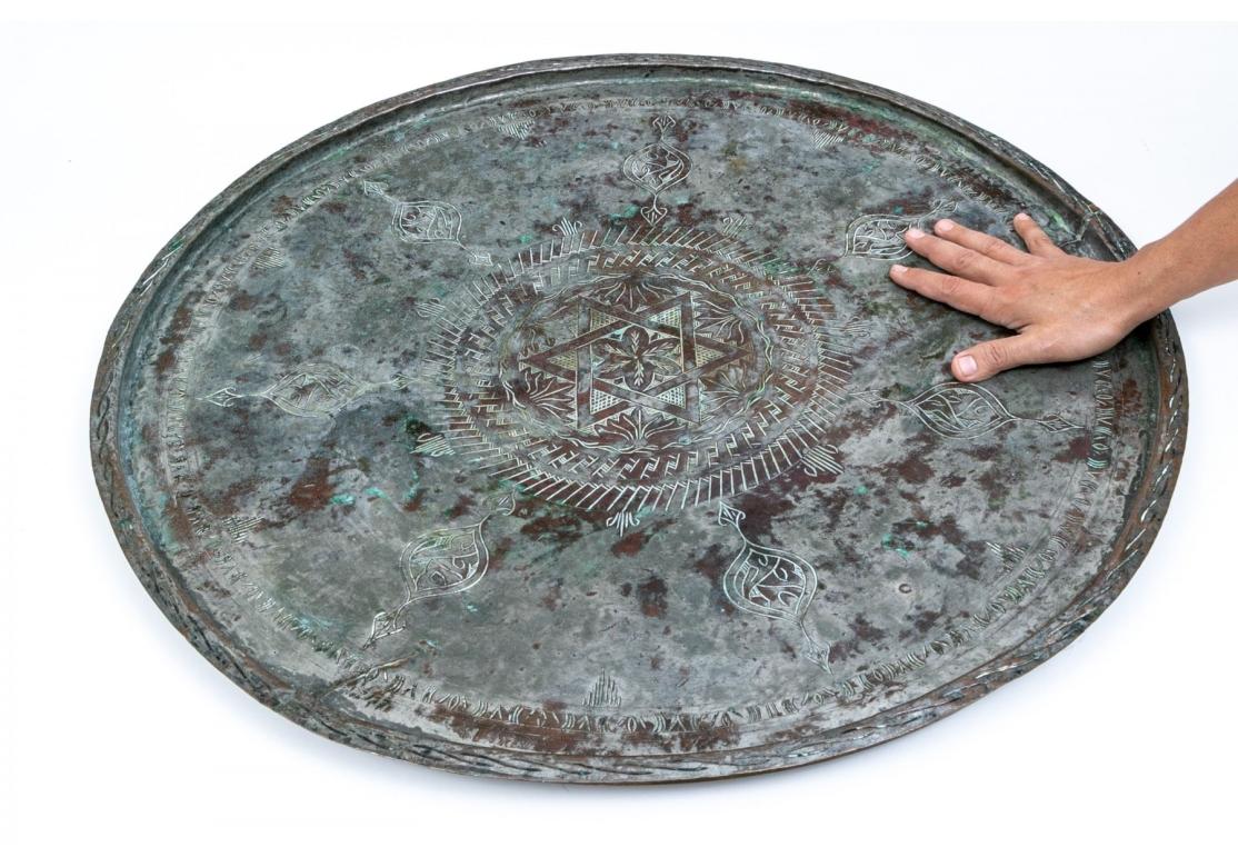 Großes, rundes Tablett mit zentralem Davidstern, eingeschnittenen Verzierungen mit Blumen und geometrischen Motiven und Grünspanpatina.
Präsentiert sich sehr gut. 

Abmessungen: 30