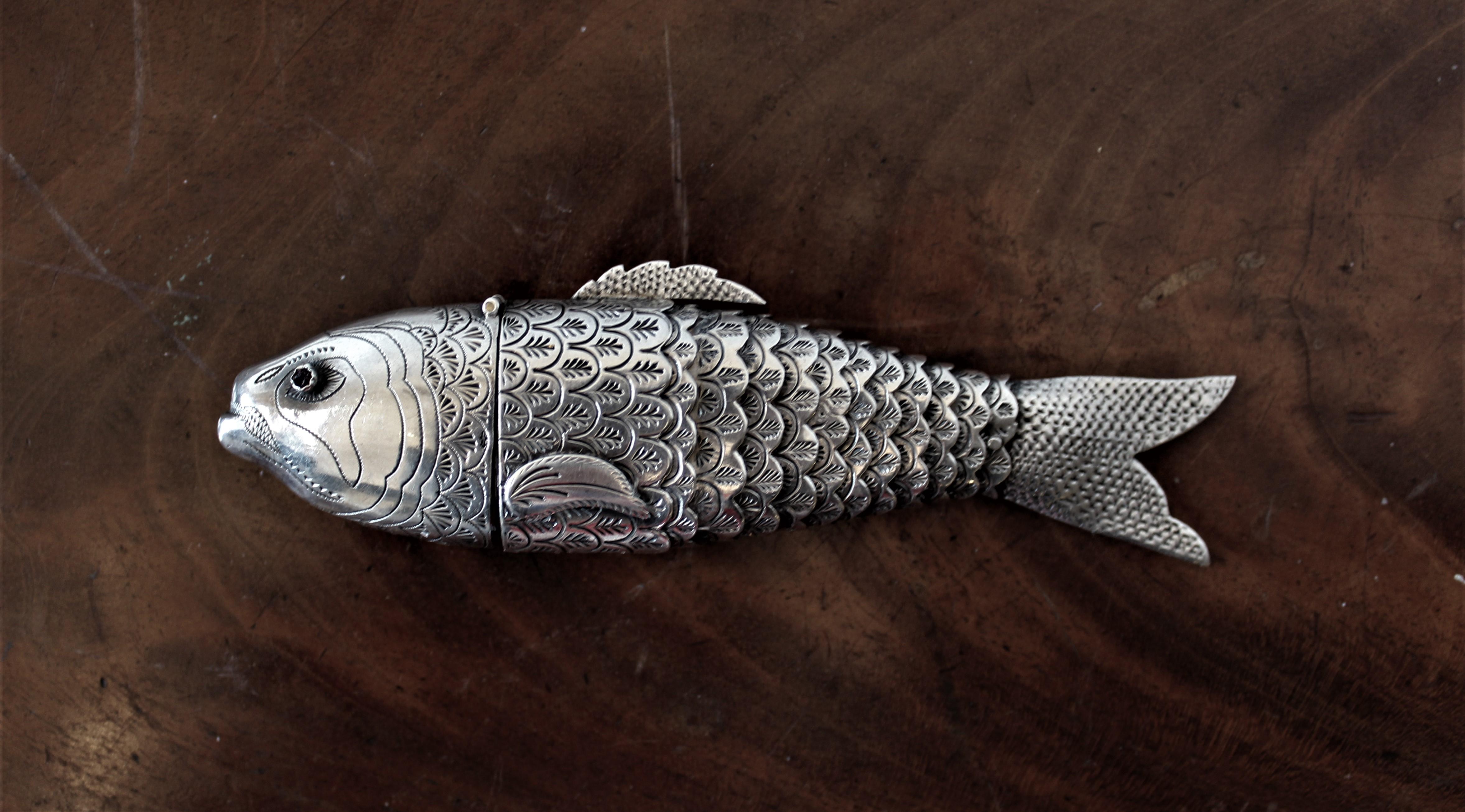 This large Judaica articulated sterling silver figural carp spice holder was likely made in Germany during the early 20th century. The spice holder is highly engraved and has inlaid eyes composed of red semi precious stones. The head is hinged and
