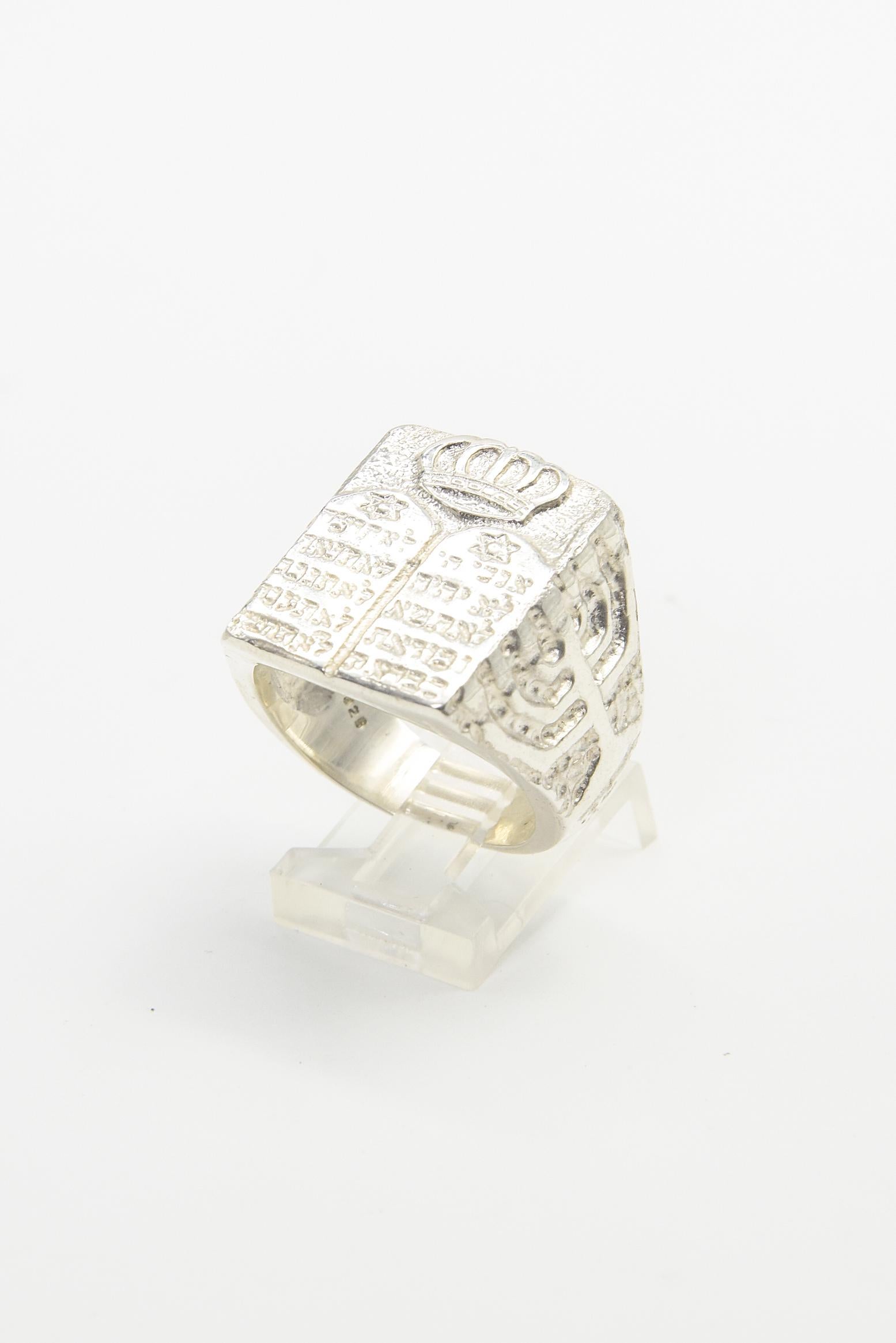 Impressive sterling silver ring featuring the Ten Commandments and a Torah Crown on the front. The Judaica theme is continued with one side having the Star of David and the other side having a Menorah.  The background is textured and the design and