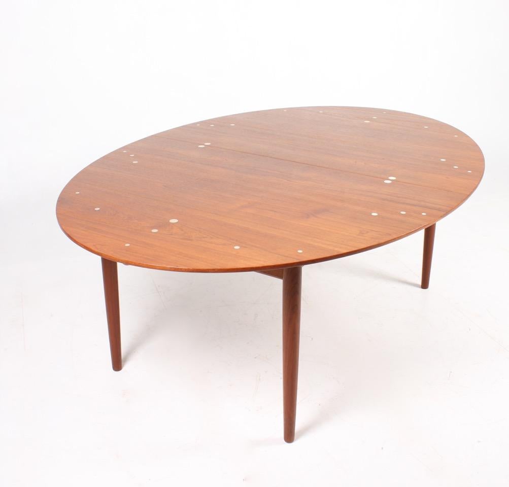 Large oval dining table in teak with coin inlays in sterling silver. Designed by Finn Juhl M.A.A. for Niels Vodder cabinetmakers in 1949. Made in Denmark. Great original condition.

Total length 310 cm (excluding the two leaves à 55 cm = length