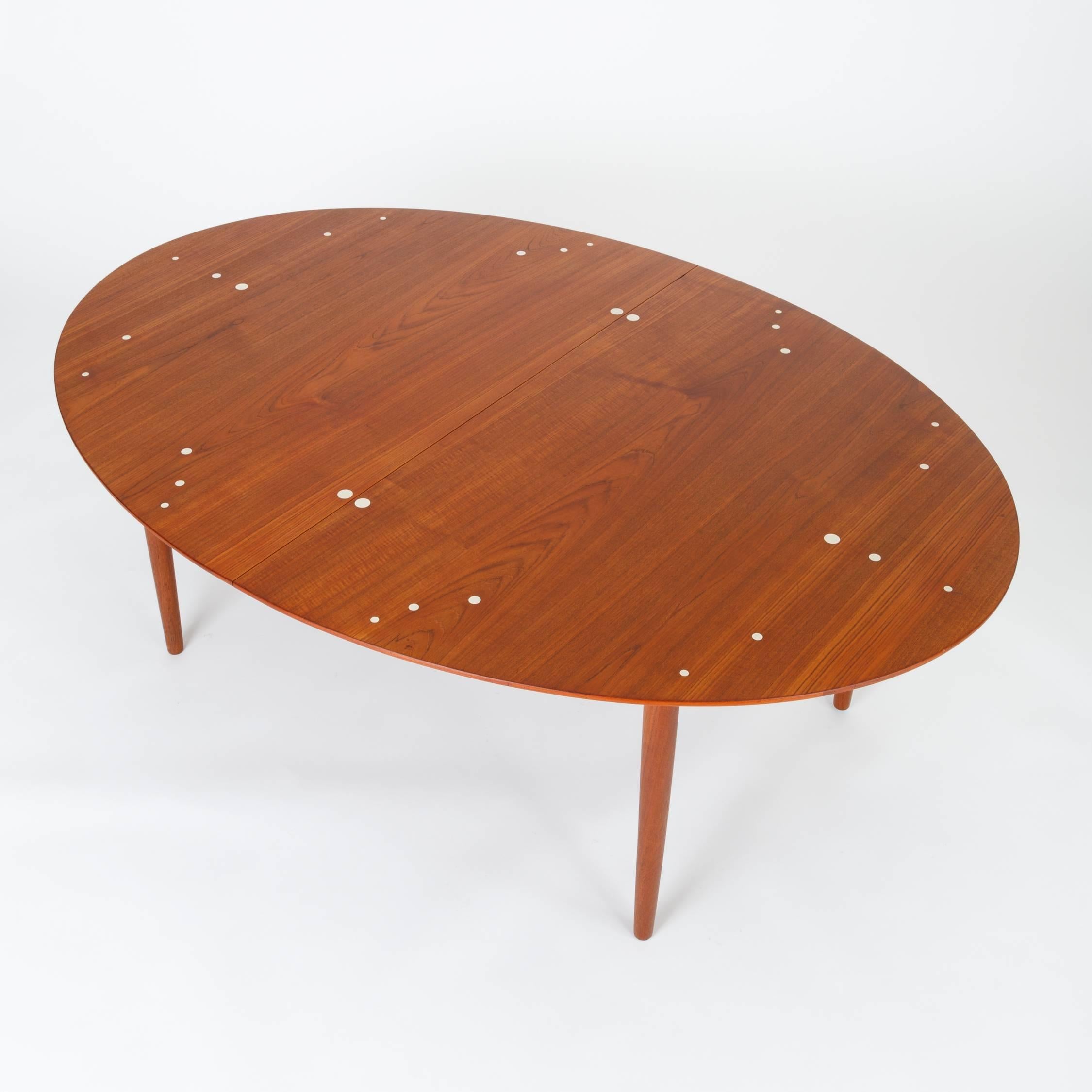 An extendable Danish teak dining table with sterling silver inlay designed by Finn Juhl and produced by cabinetmaker Niels Vodder. The colloquially-named Judas table has 30 sterling silver 'coin' inlays, demarcating the placement of chairs and place