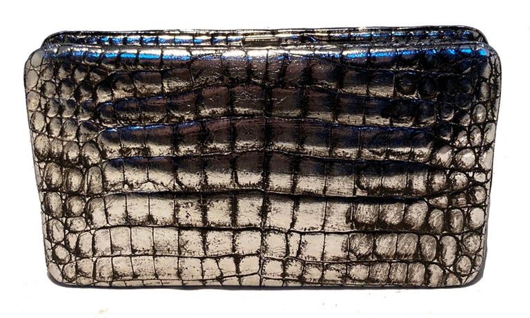 Judith Leiber Antiqued Silver Alligator Clutch in excellent condition. Antiqued silver alligator exterior with black accents and top lifting closure. Black satin lined interior with one slit and one zipped side pockets. No stains, smells or scuffs.