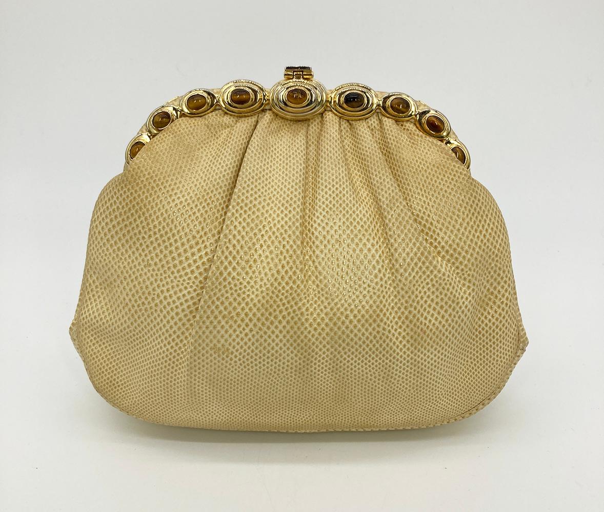 Judith Leiber Beige Lizard Tiger Eye Gemstone Clutch in fair condition. Beige lizard leather trimmed with gold hardware and tiger eye gemstones along top edge. Top center lift latch closure opens to a cream nylon lined interior with two slit side