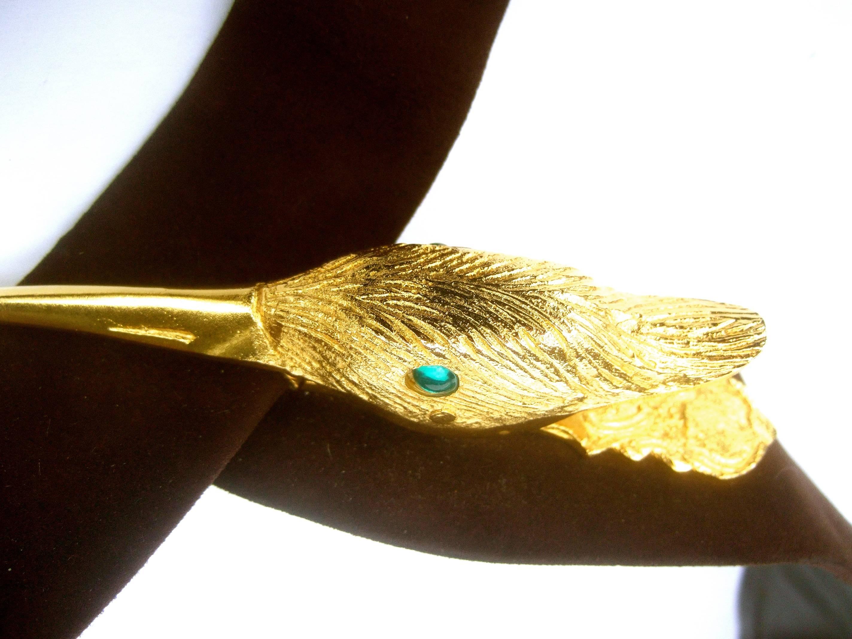 Judith Leiber exotic gilt metal bird buckle belt circa 1980s
The avant garde belt is designed with a stylized gilt metal
birds head that serves as the buckle 

The birds head has etched detail that emulates feathers
Embellished with a set of emerald