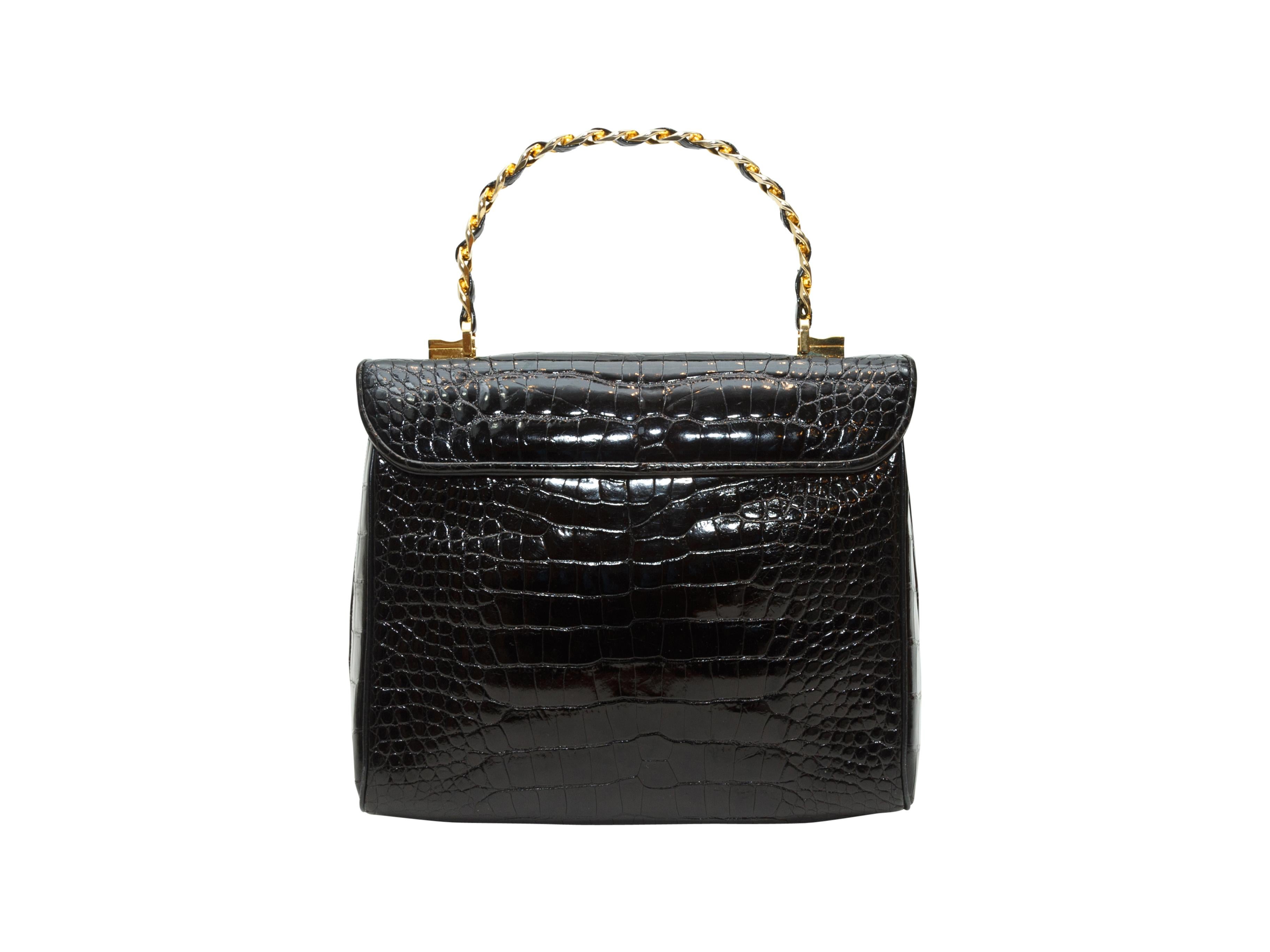 Product details: Vintage black alligator skin handbag by Judith Leiber. Gold-tone metal top handle. Closure at front. 8.5
