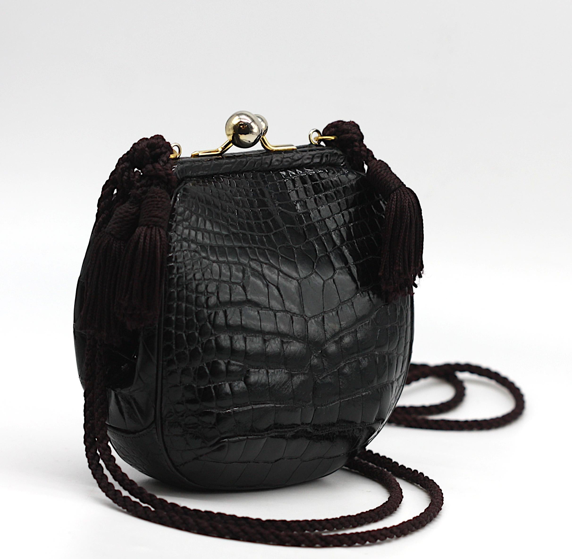 Porte-monnaie en alligator noir de Judith Leiber

Judith Leiber signe un sac du soir raffiné et distinctif, de forme circulaire, en alligator noir poli. La silhouette élégante est fermée par un fermoir à double sphère et s'ouvre sur un intérieur