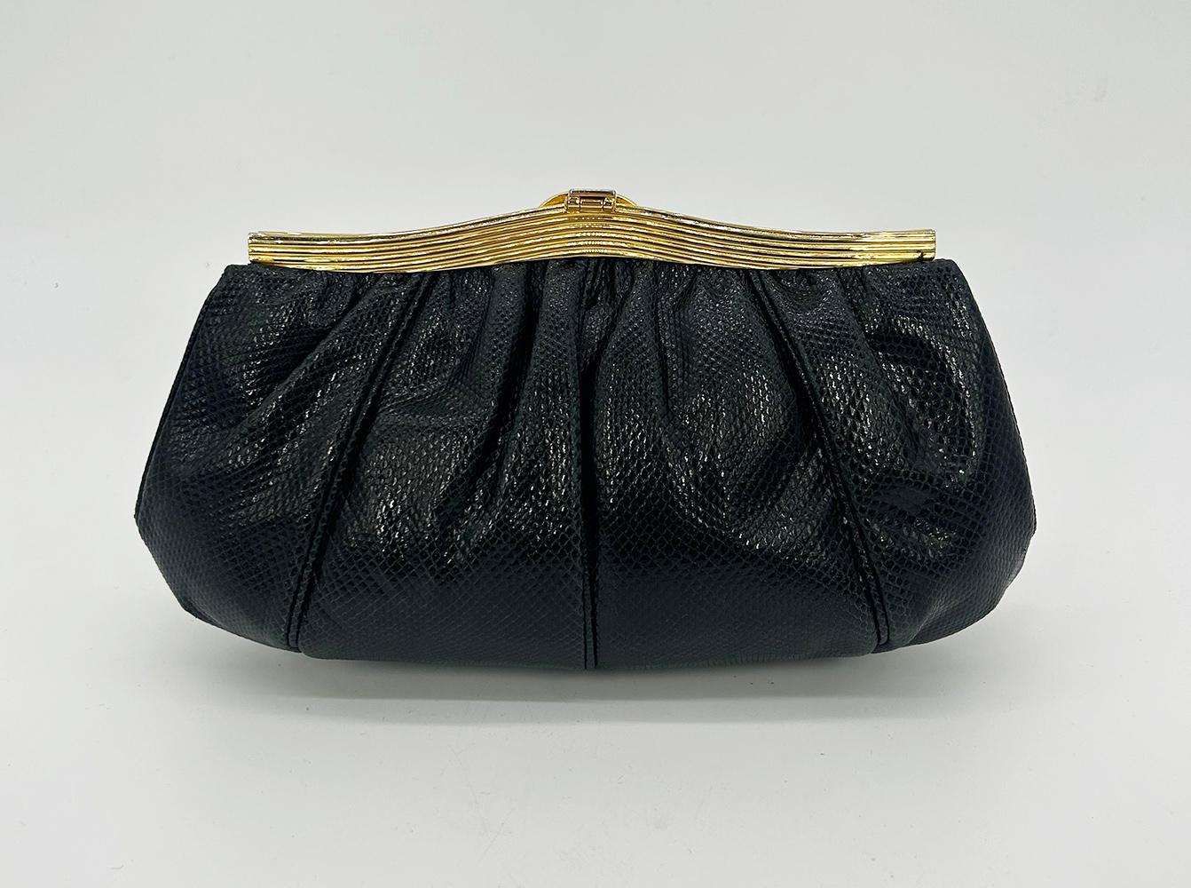 Judith Leiber Black Lizard Lion Head Clutch in very good condition. Black pleated lizard leather exterior trimmed with gold hardware and unique lion head embossed center detail. Lift latch top center closure opens to a black satin lined interior