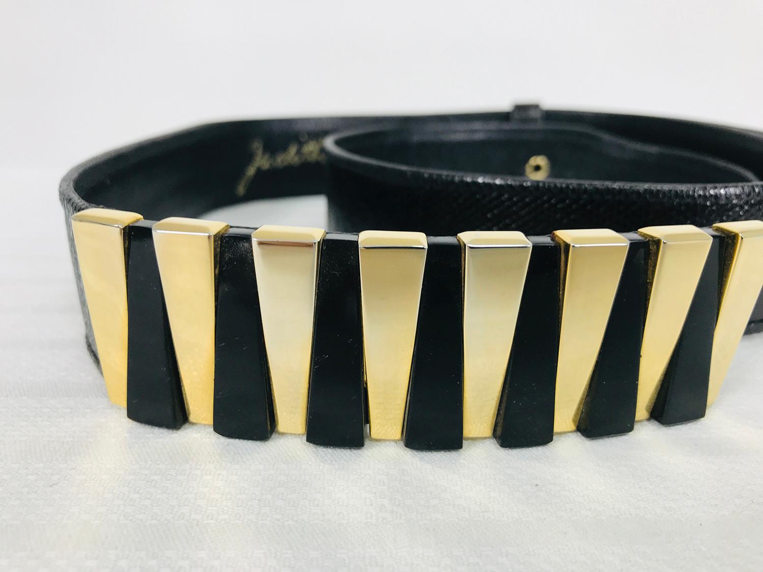 Judith Leiber black Lucite & gold metal buckle, black karung lizard adjustable belt. The belt is black karung lizard and slightly contoured, it adjusts by sliding. The buckle is long and has a prong for closure there is a single hole of gold metal.