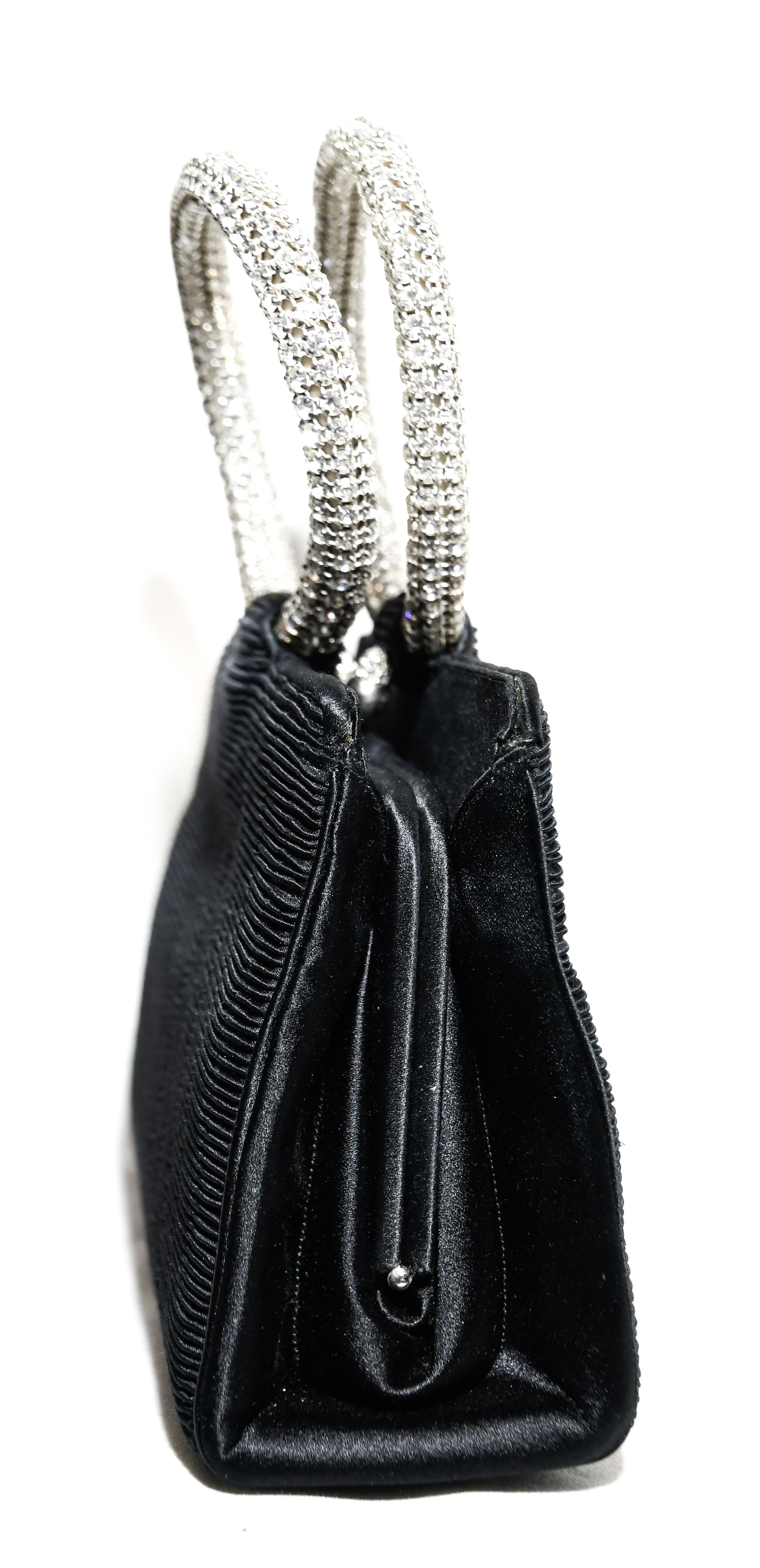 Judith Leiber black ribbed satin  bag incorporates two round  rhinestone covered  top handles.  For closure a rhinestone covered kiss lock snap that opens to a black satin two pocket compartment.  Handle drop: 3.50