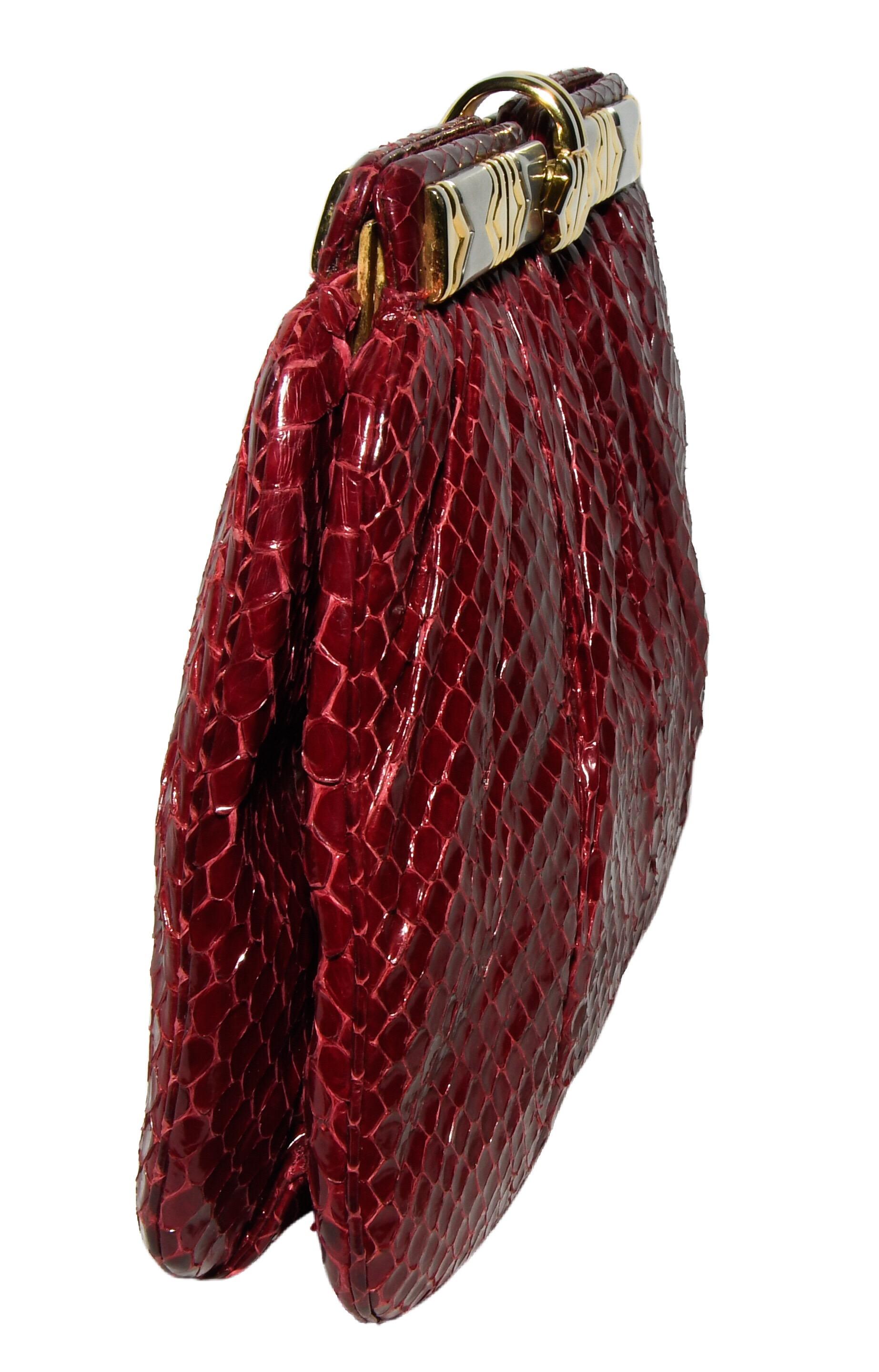 Judith Leiber burgundy python leather clutch includes a python leather shoulder strap.  This clutch contains a center compartment that is lined in red grosgrain with 2 side slit pockets.  The outside is gathered  on both sides.  The top handle metal