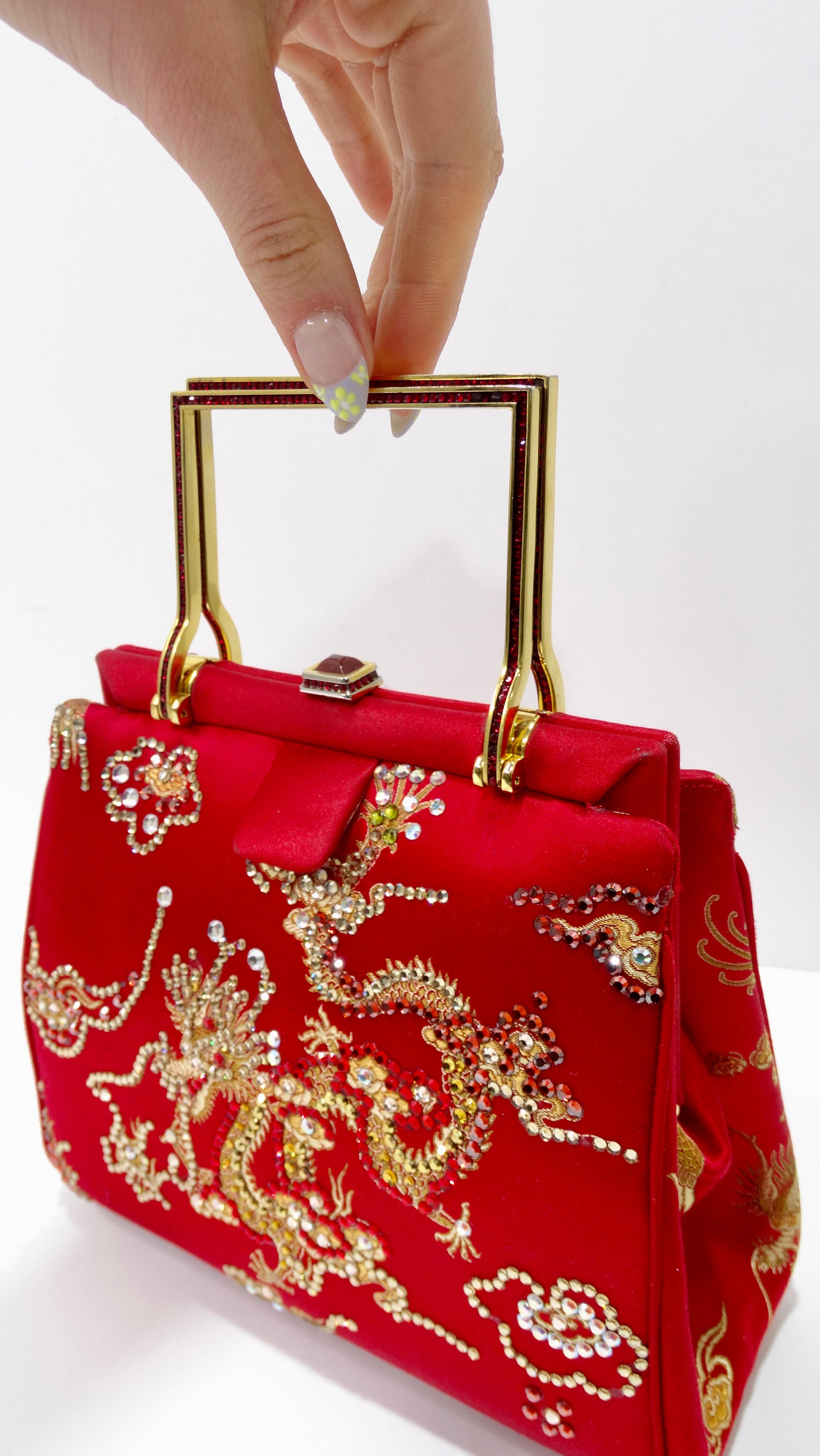 Elevate your look with this amazing Leiber! Circa 1970s, this red satin bag features a gorgeous rhinestoned Chinese dragon motif, gold hardware, dual top handles with red rhinestones, and a decorative top closure. Interior is lined with red satin